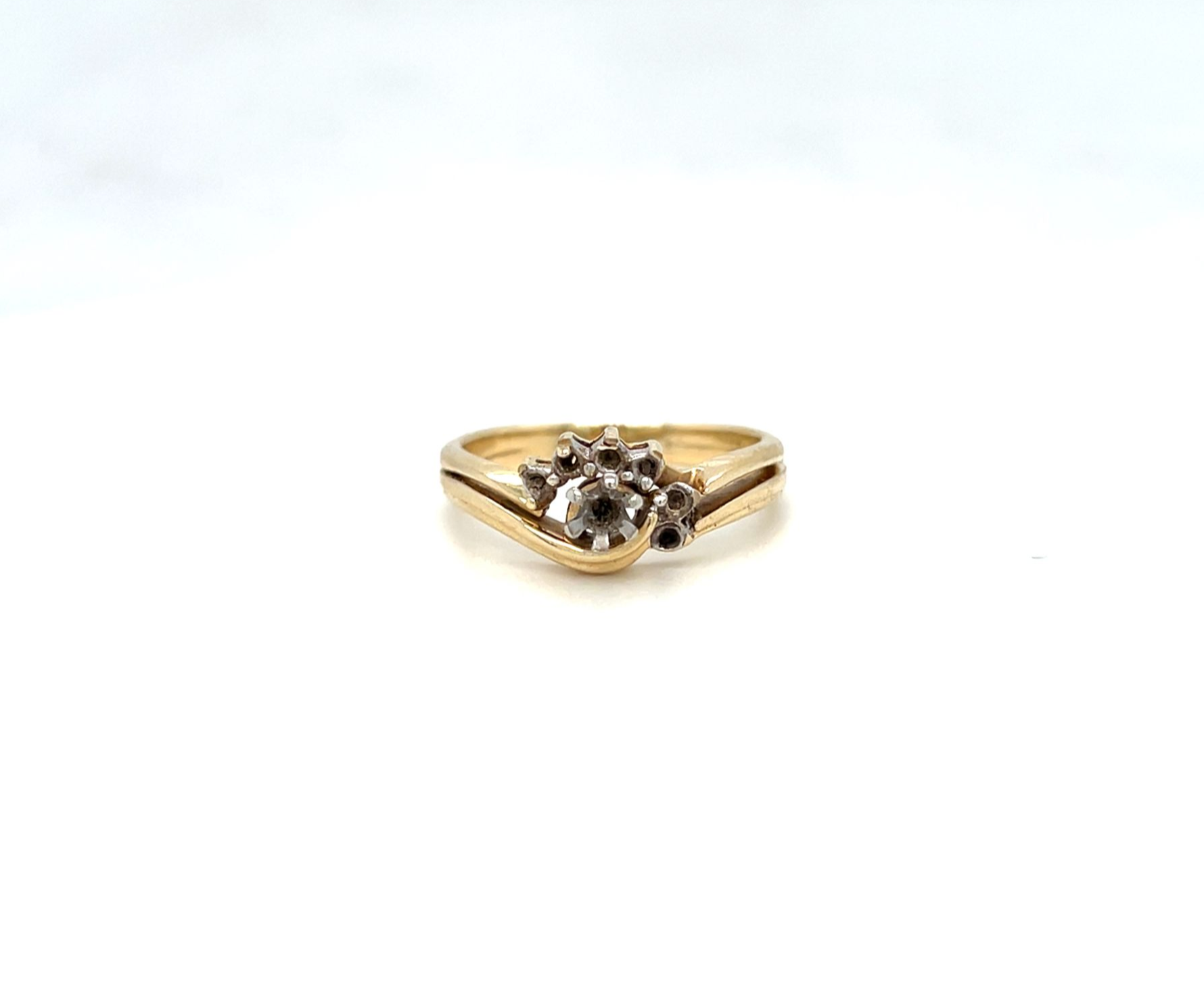 Gold ring with a cluster of small stones in the center, set against a white background.