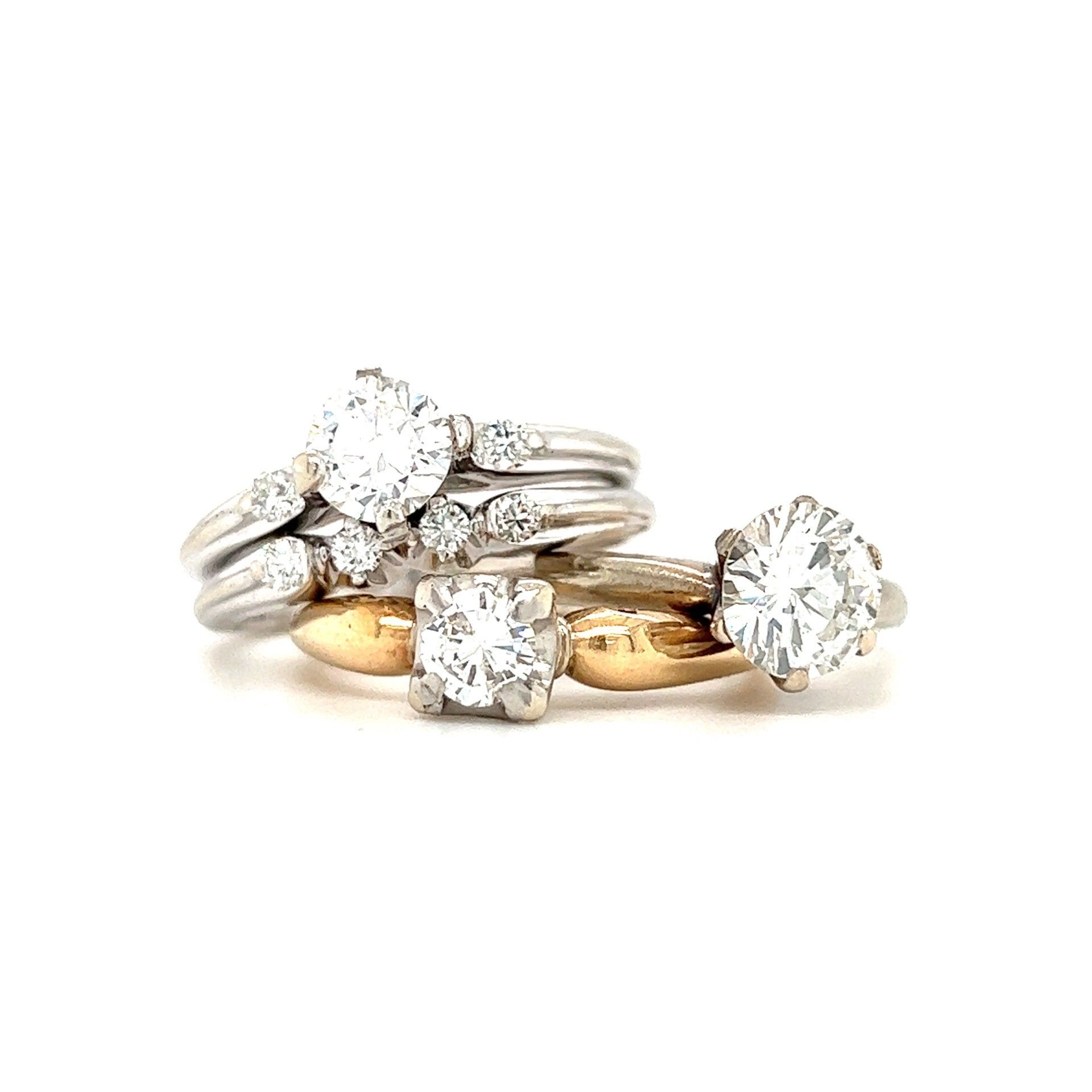 Four diamond engagement rings, various settings, stacked on a white surface.