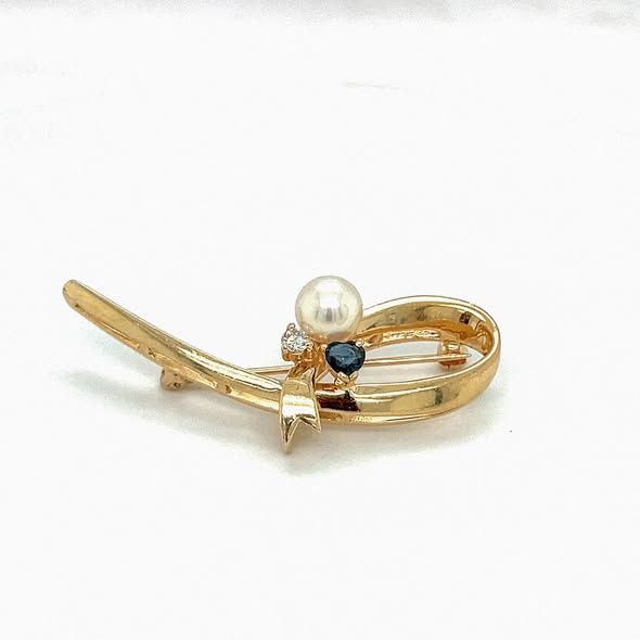 Gold brooch with pearl, sapphire, and diamond accents.