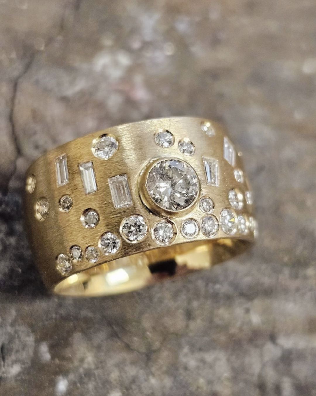 Gold band ring with various sized diamonds.