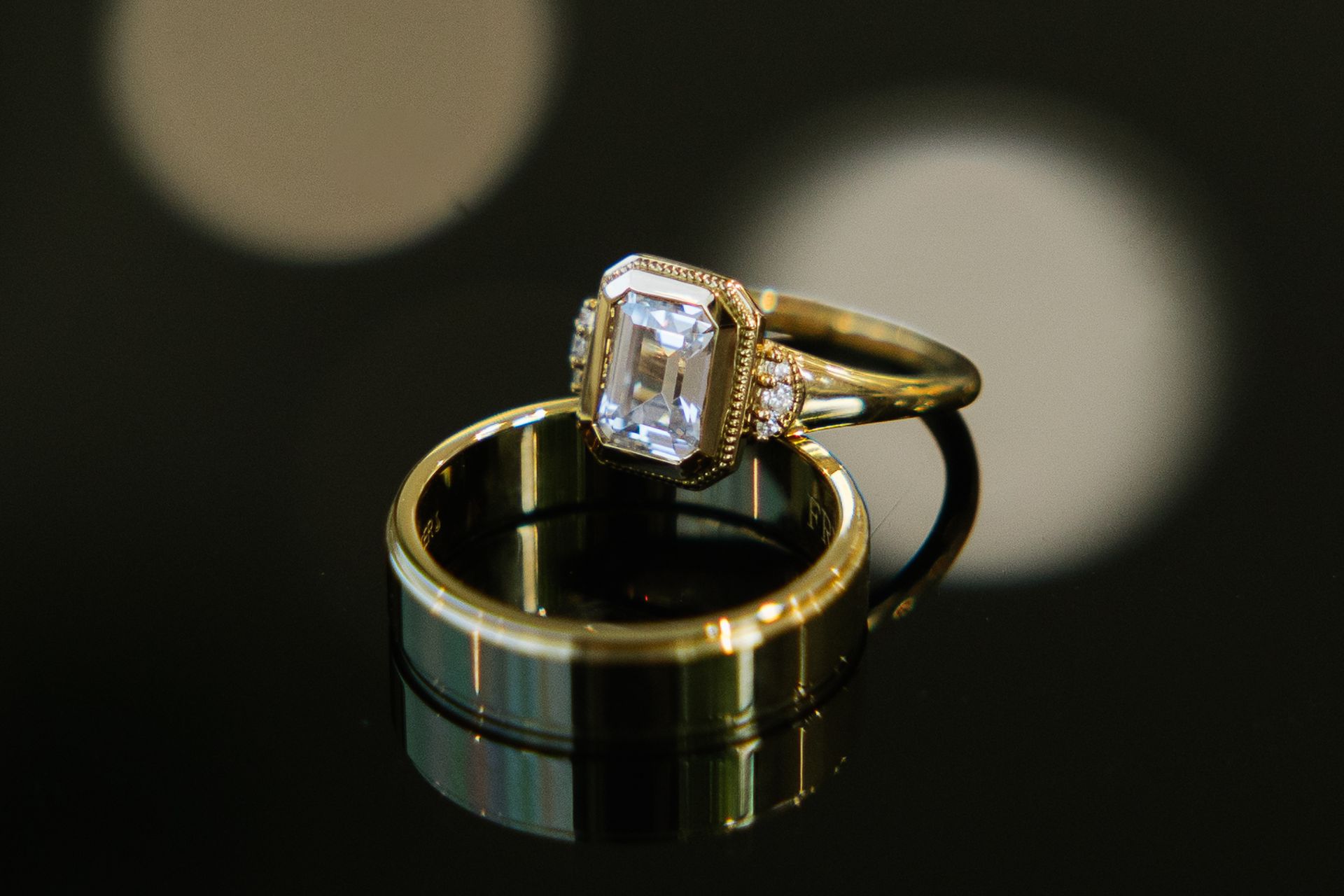 A close up of a wedding ring and engagement ring on a table.