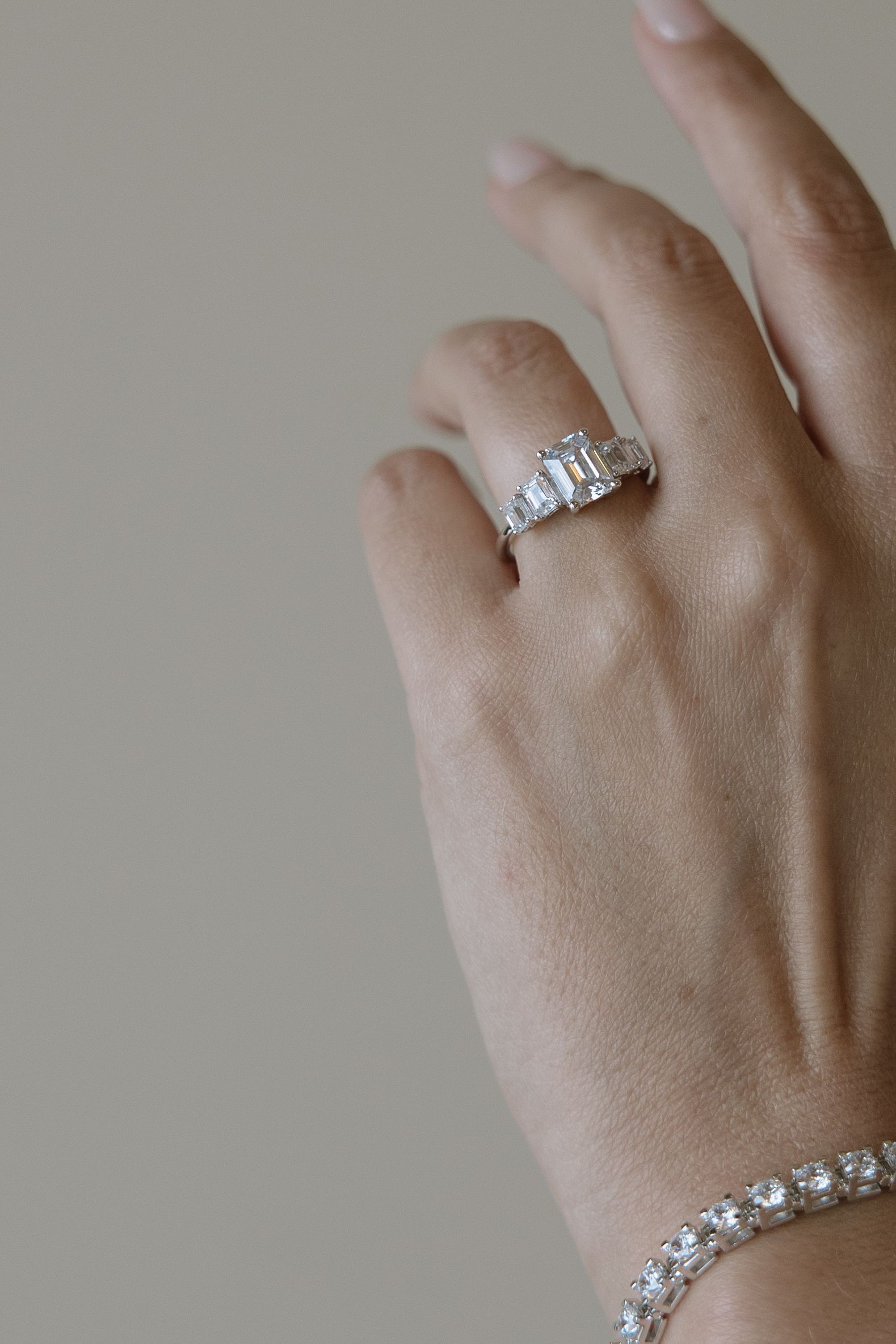 A woman is wearing a ring and a bracelet on her left hand.