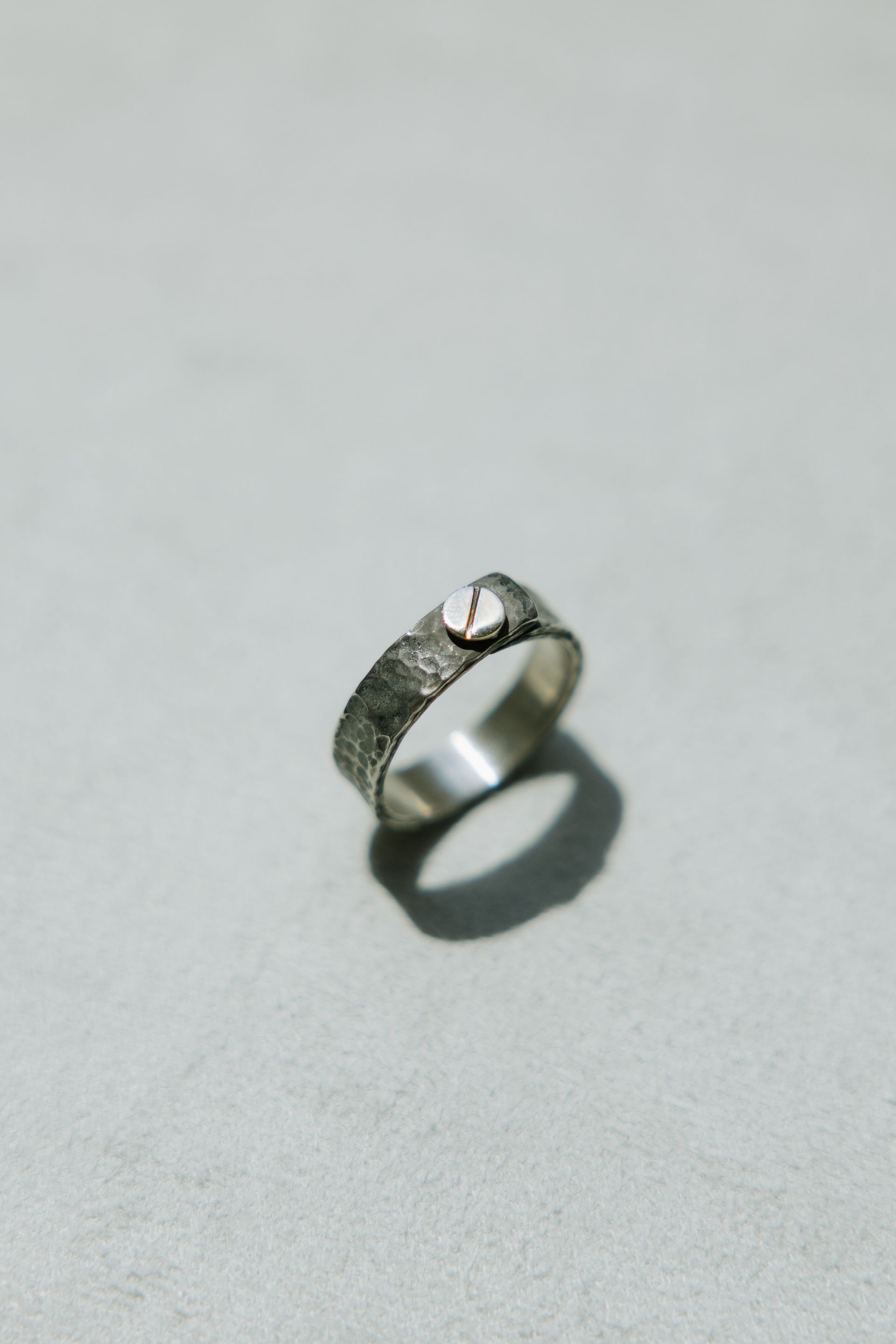 A silver ring is sitting on a gray surface.