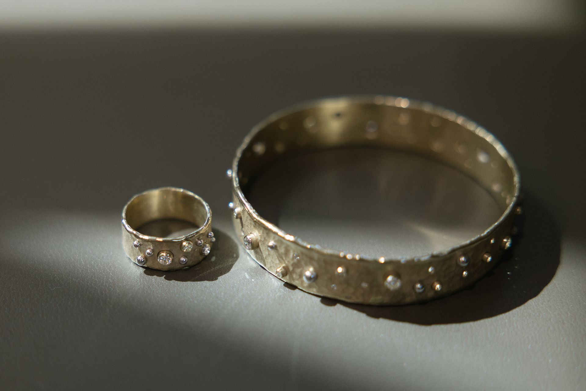 A bracelet and a ring are sitting on a table.