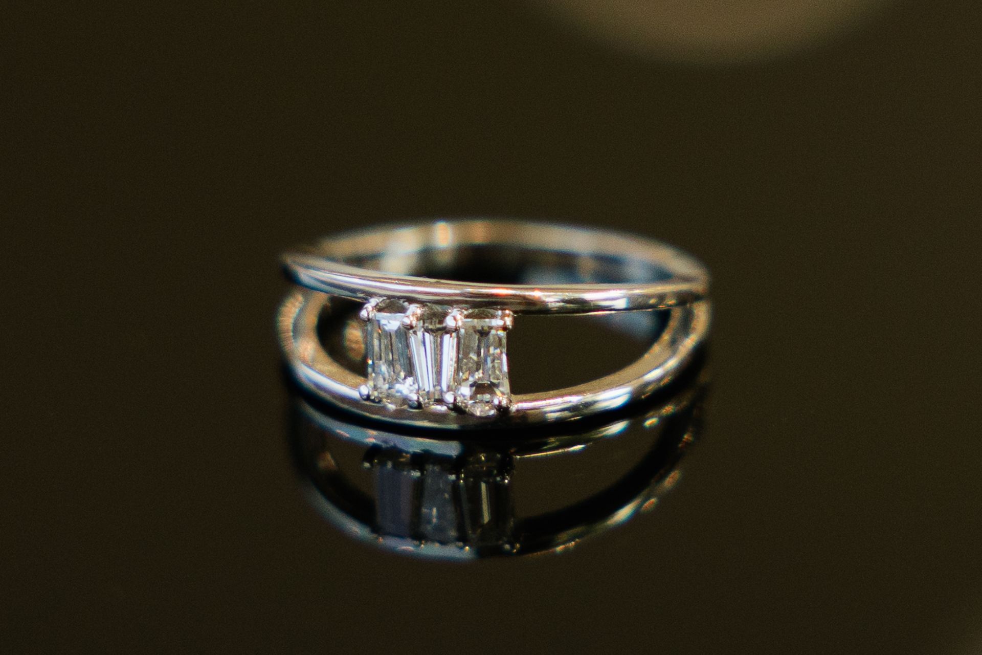 A close up of a diamond ring on a black surface.