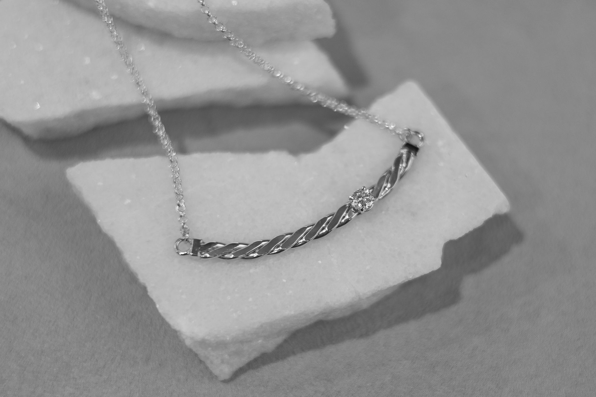 A black and white photo of a necklace on a piece of marble.