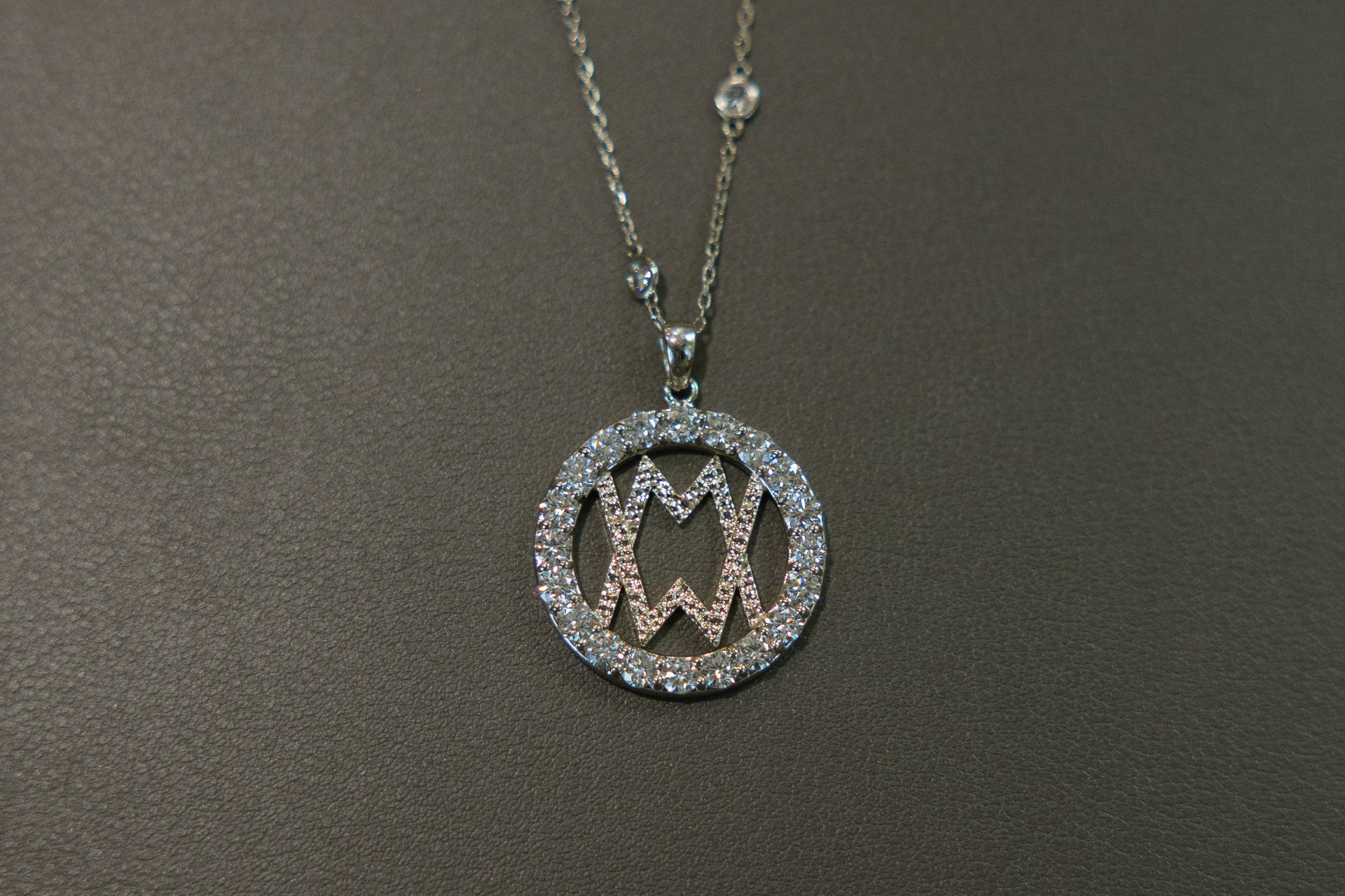 A necklace with a pendant that has the letter m on it