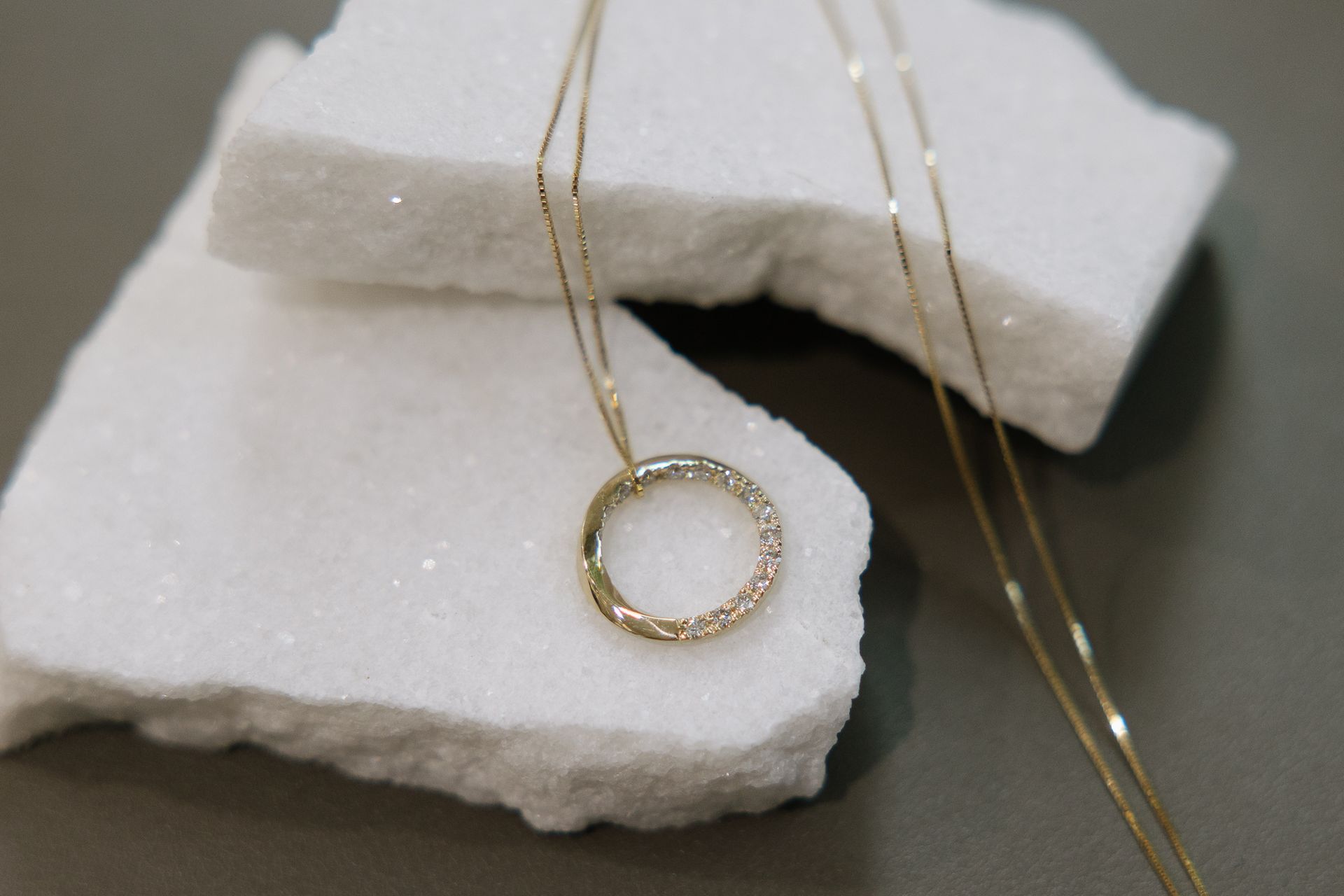 A necklace with a circle shaped pendant is sitting on a piece of styrofoam.