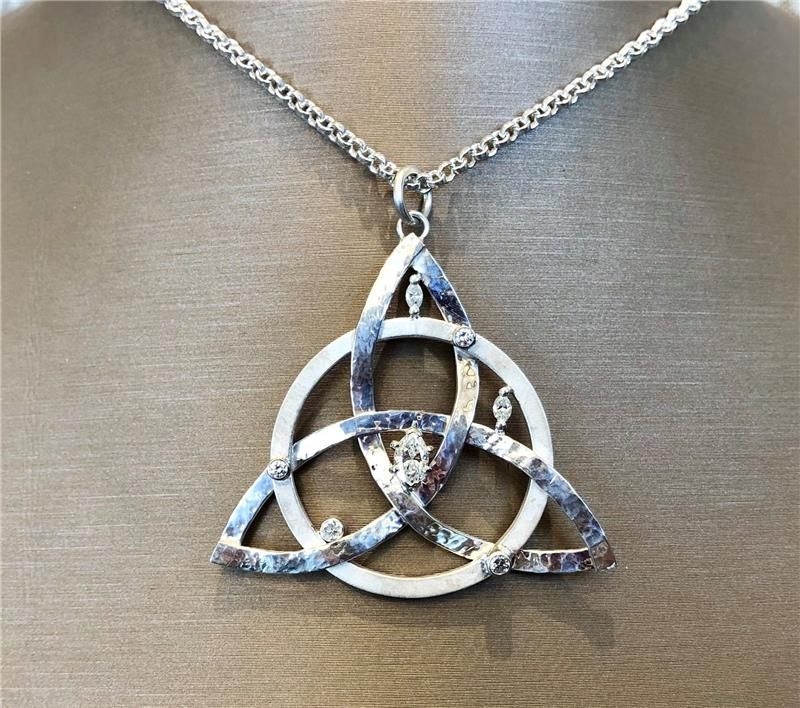 Silver Celtic knot pendant necklace on a beige background.