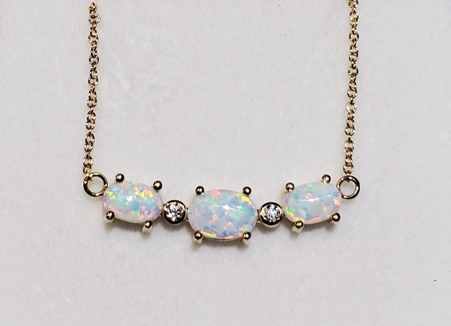 Gold necklace with three opal stones and two smaller clear gems.