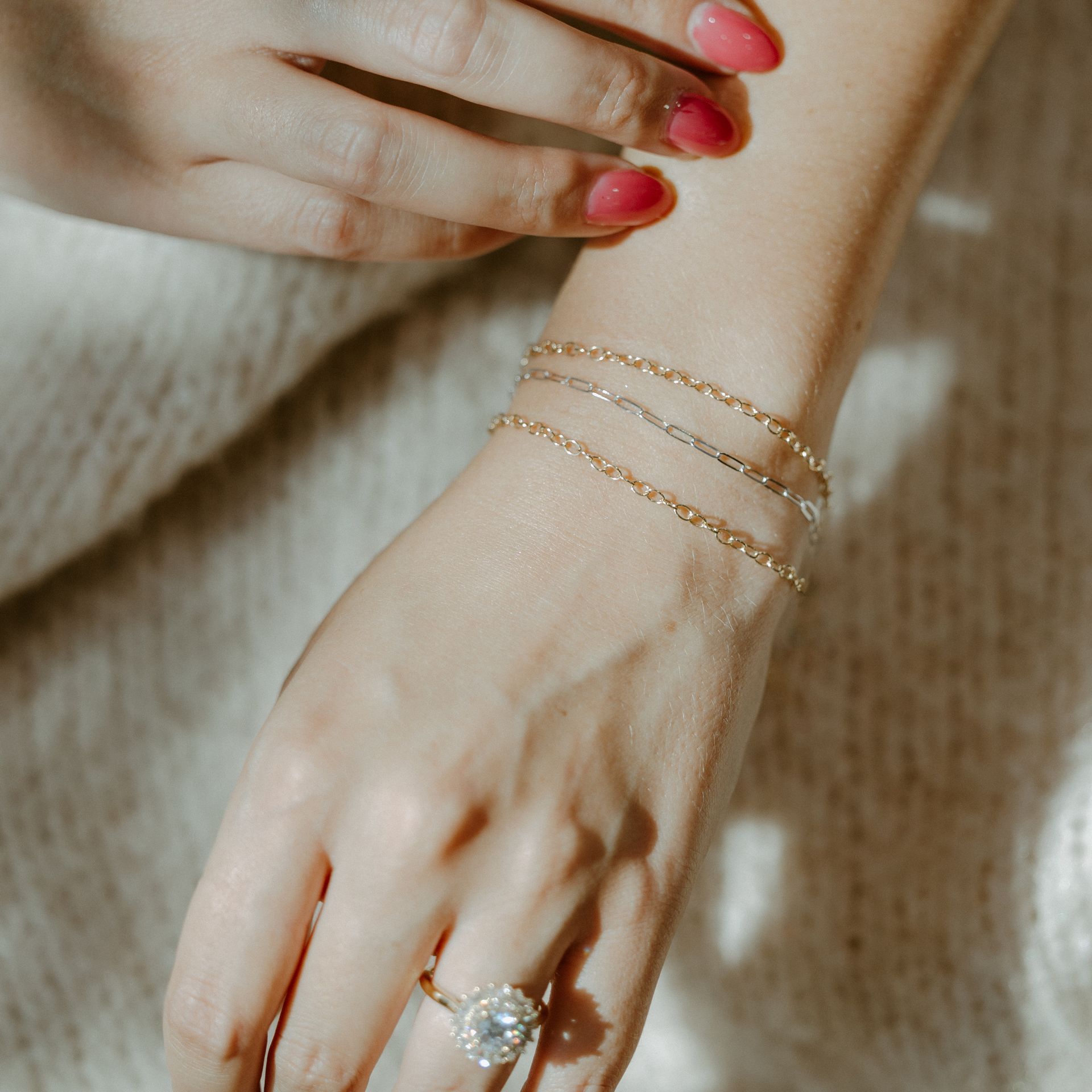Hand wearing gold bracelets and a diamond ring.