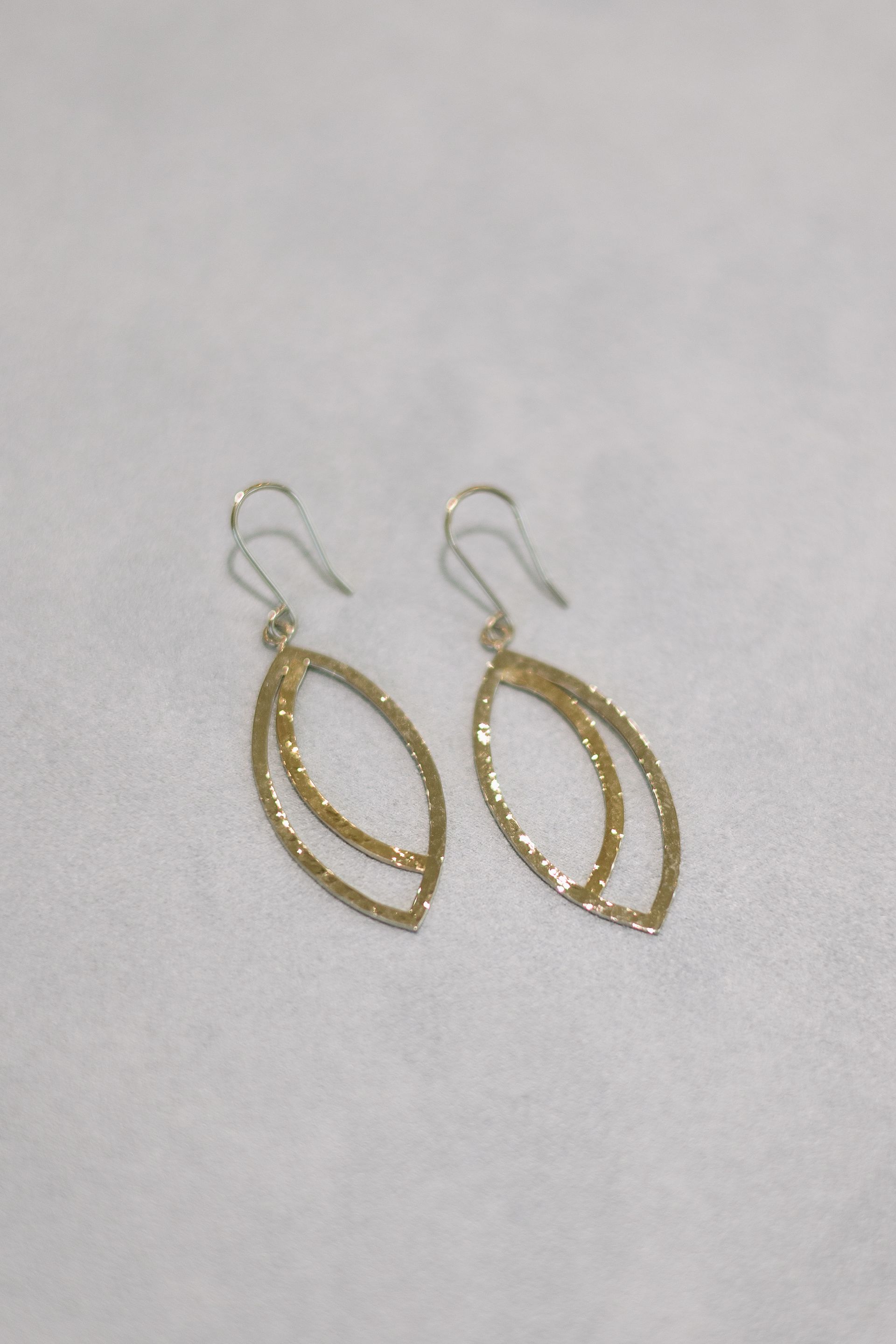 Gold, double-oval dangle earrings on a white background.