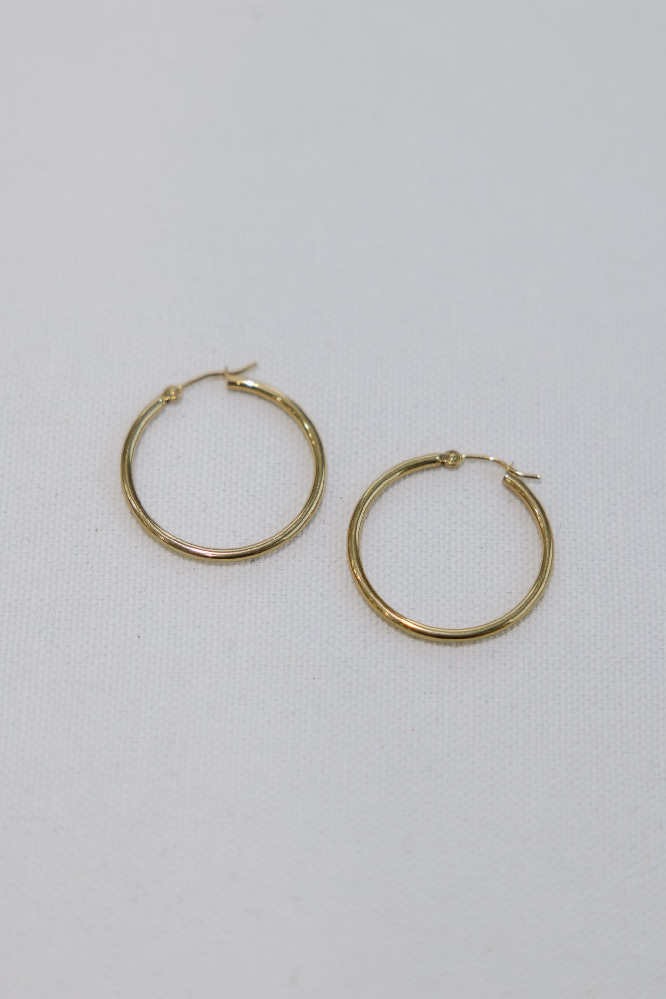 Pair of gold hoop earrings on white background.