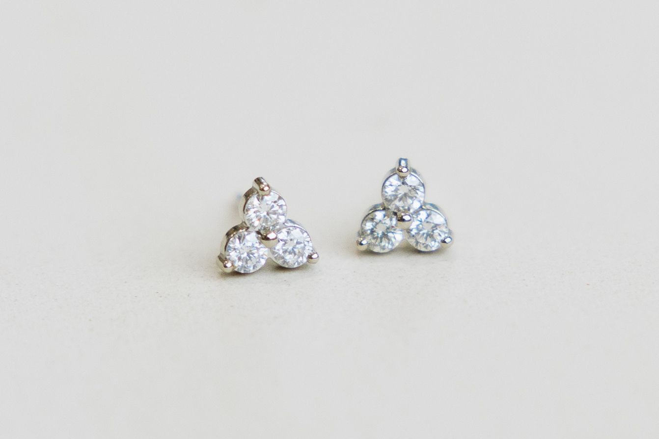 Pair of silver stud earrings, each with three clear, round gems arranged in a triangular shape.