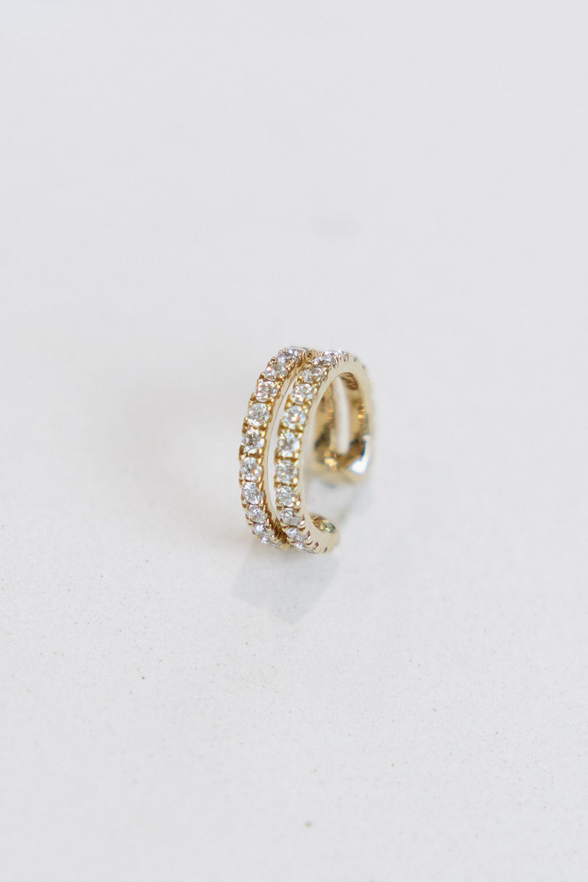 Gold ear cuff with three rows of clear gemstones.