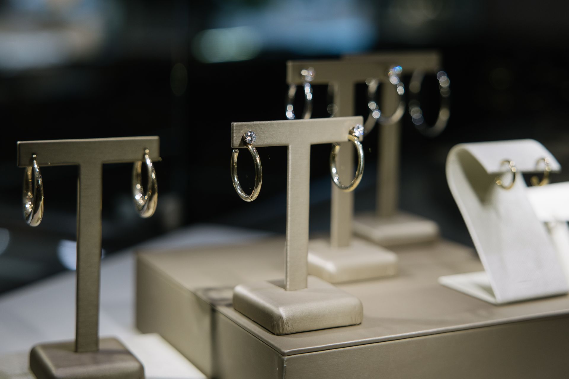 Earrings displayed on beige stands in a jewelry store.