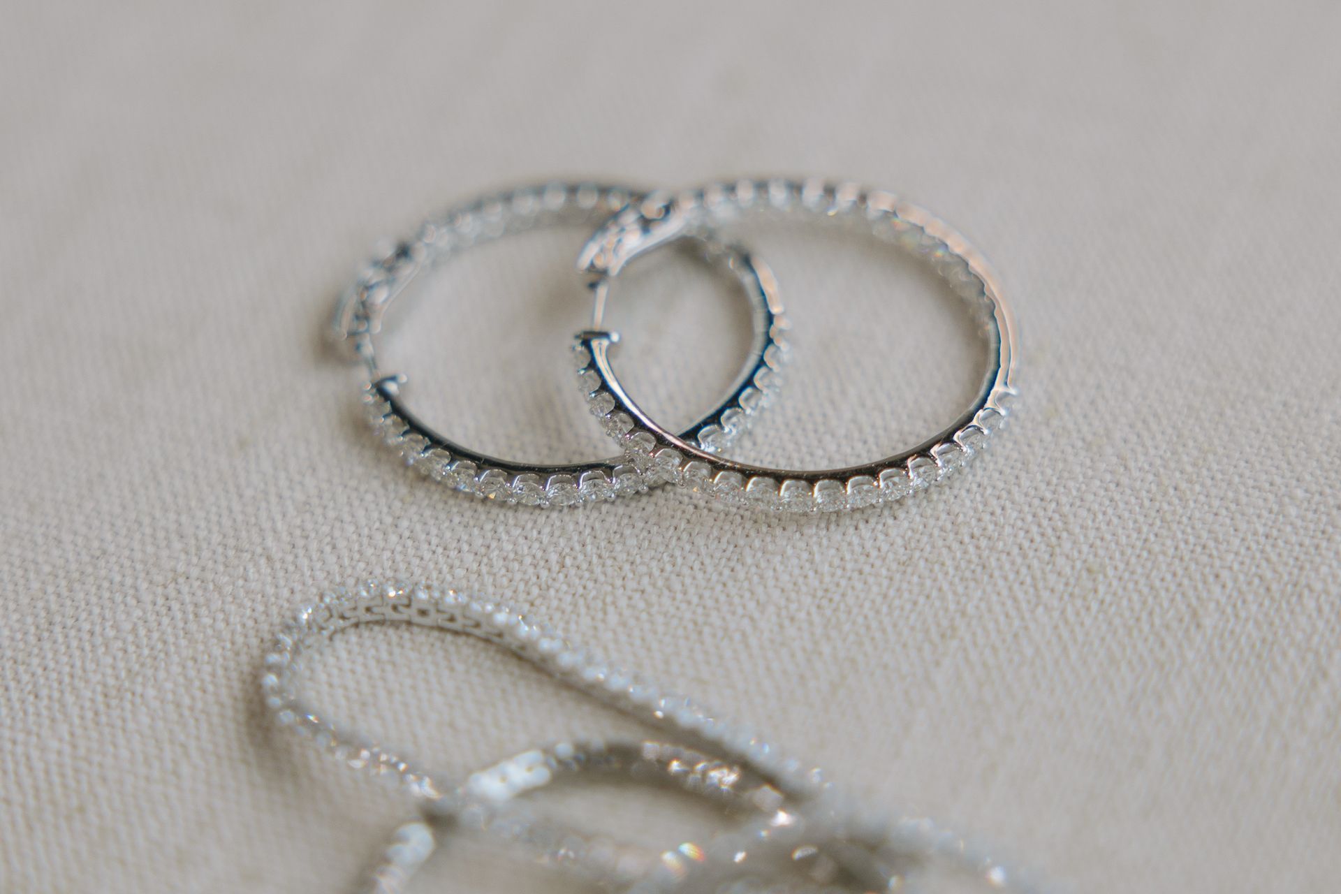 Silver hoop earrings with small, clear stones on a white background.