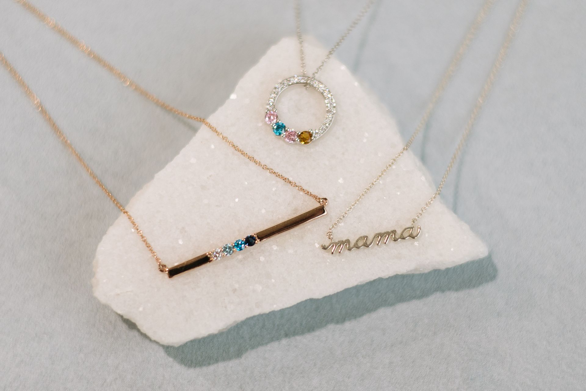 Three necklaces displayed on a white, crystalline surface; one reads 