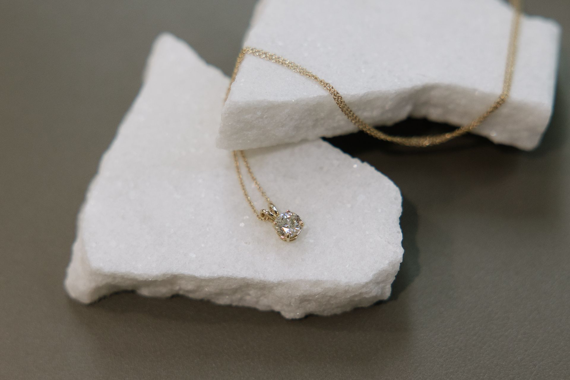 Diamond pendant necklace on white, textured surface.