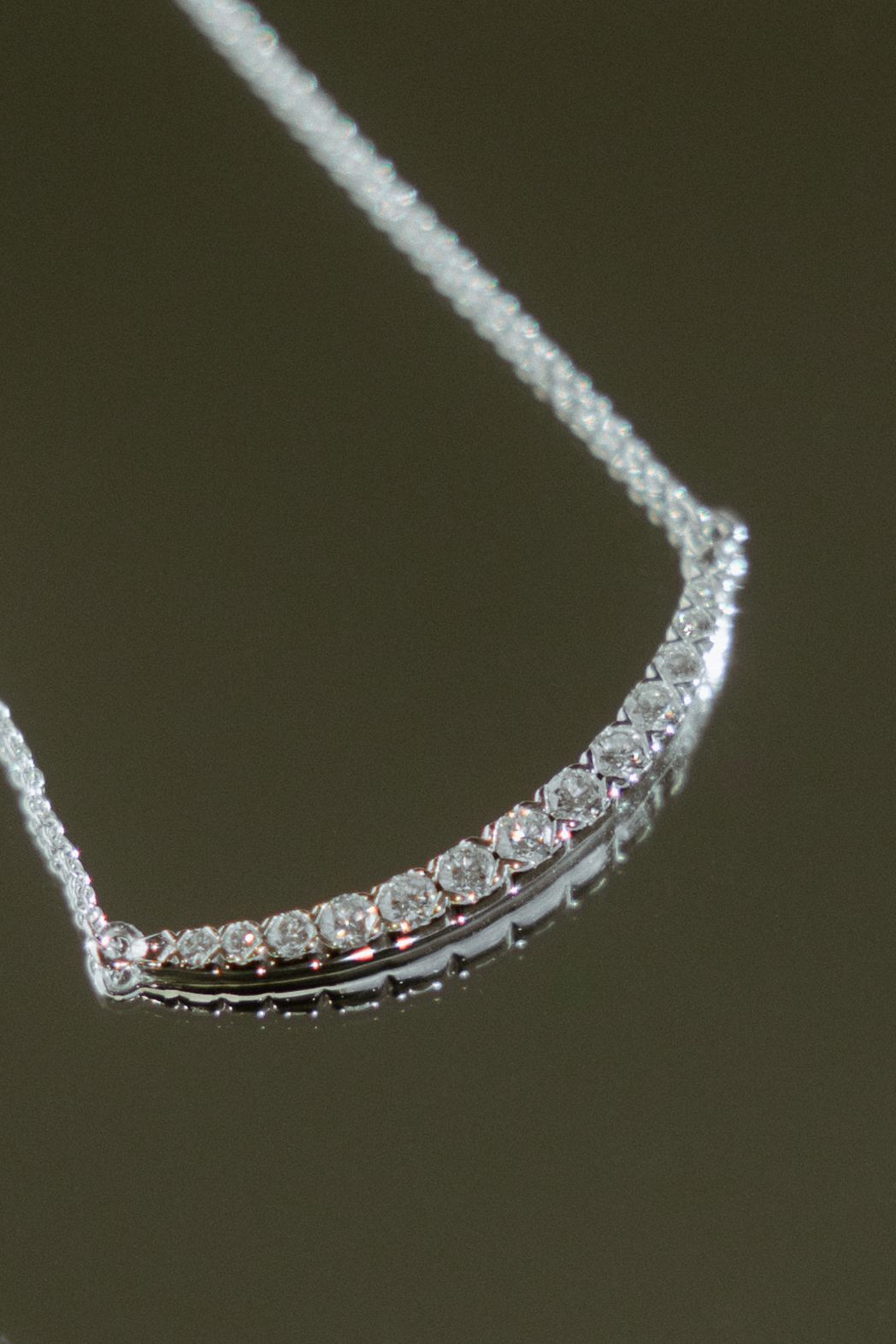 Diamond pendant necklace, curved bar of diamonds on a silver chain.