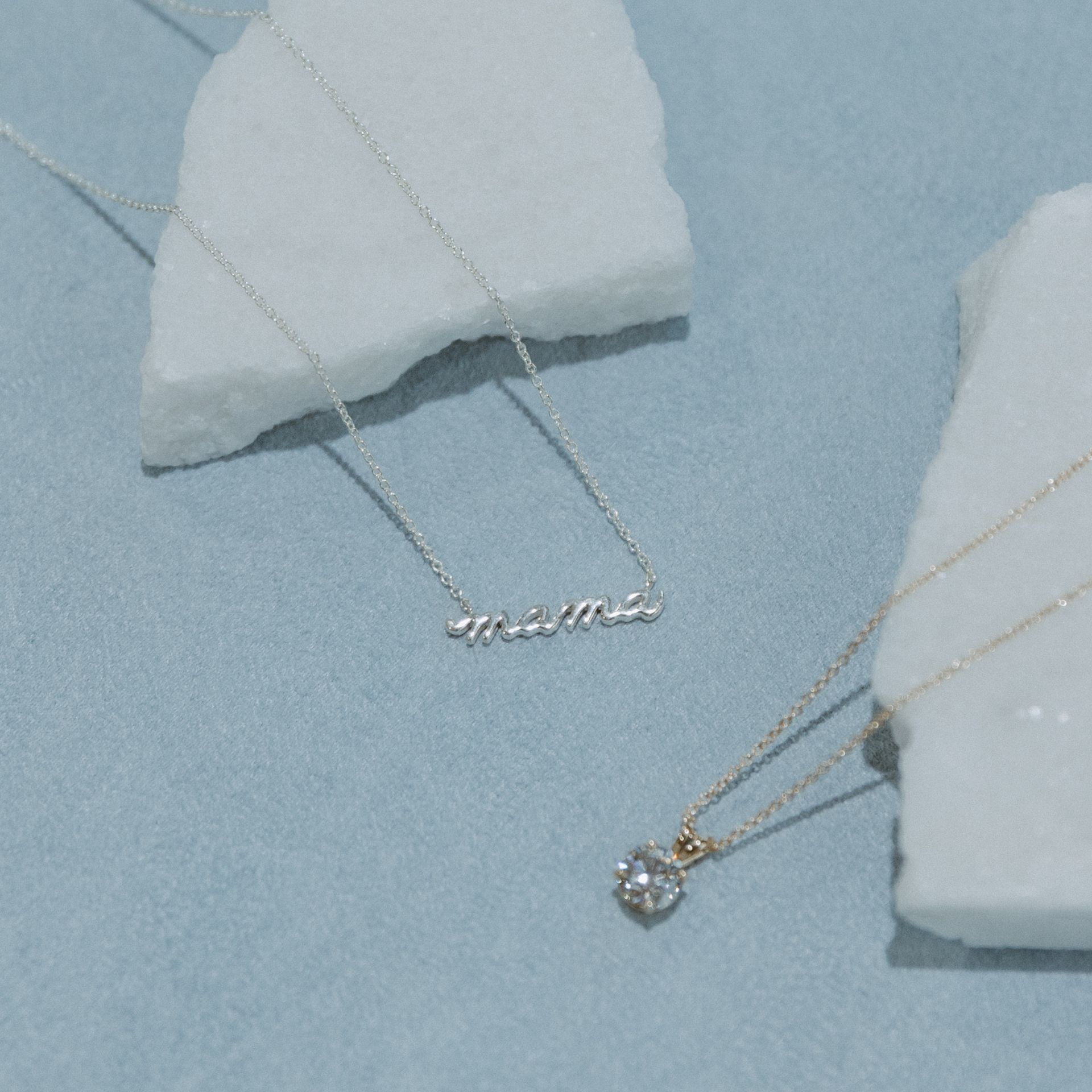 Two necklaces on light blue surface, one with 