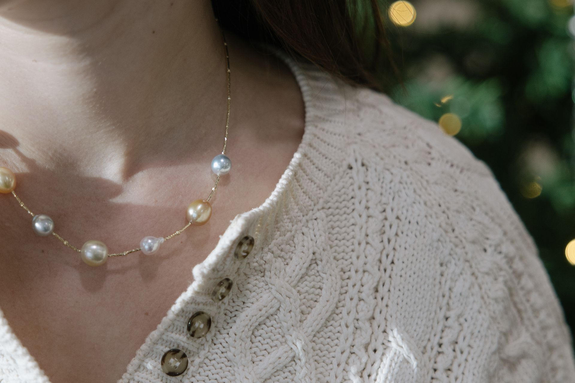 Woman wearing a pearl necklace and cream-colored sweater.