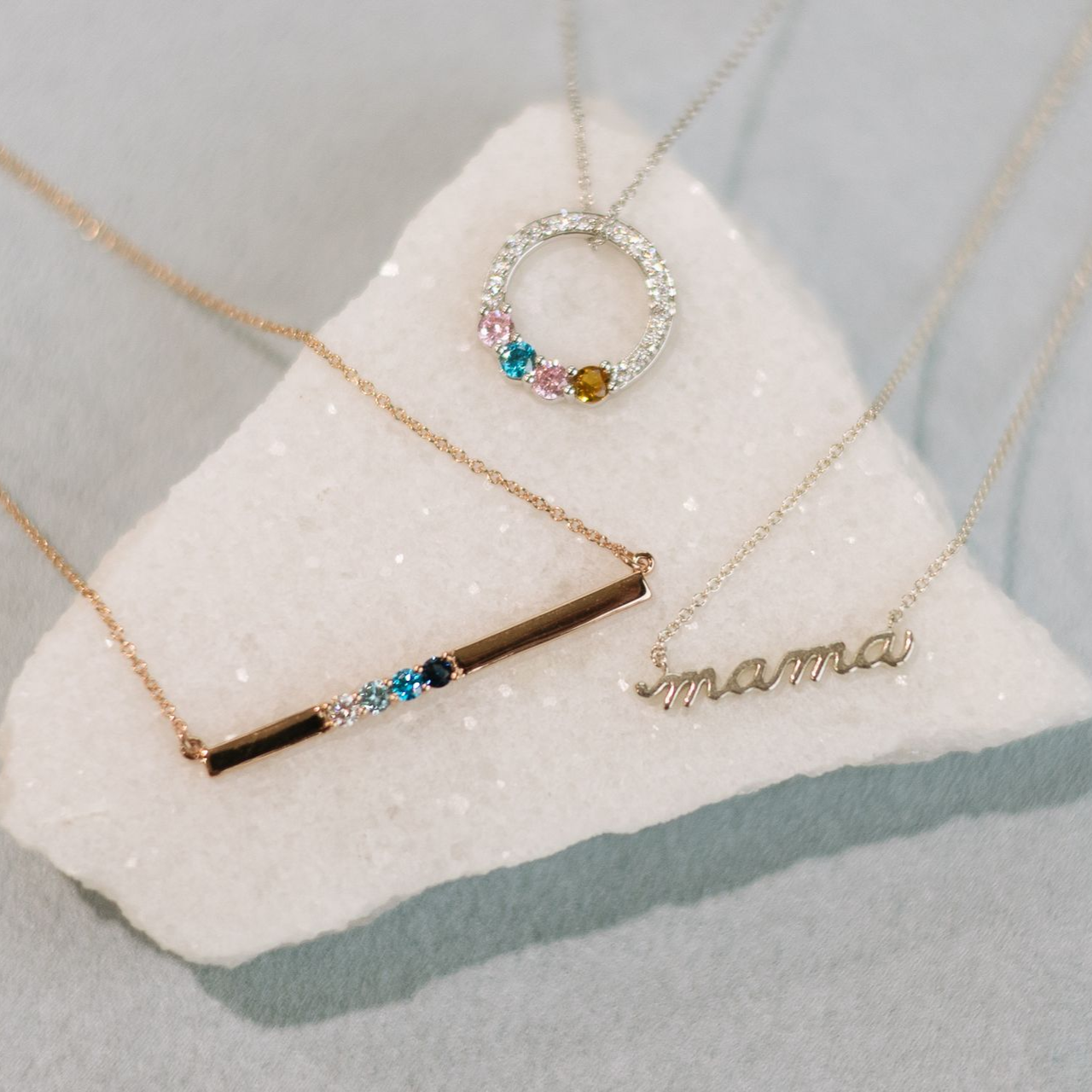 Three necklaces displayed on a white, crystalline surface; one reads 