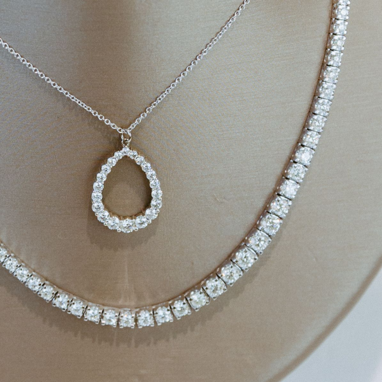 Two diamond necklaces on a mannequin. One has a teardrop pendant.