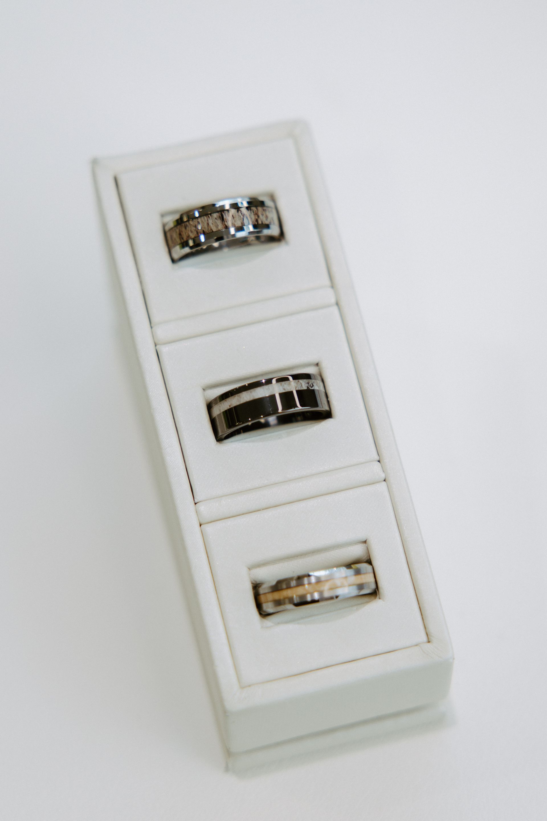 Three rings displayed in individual white compartments within a white rectangular box.