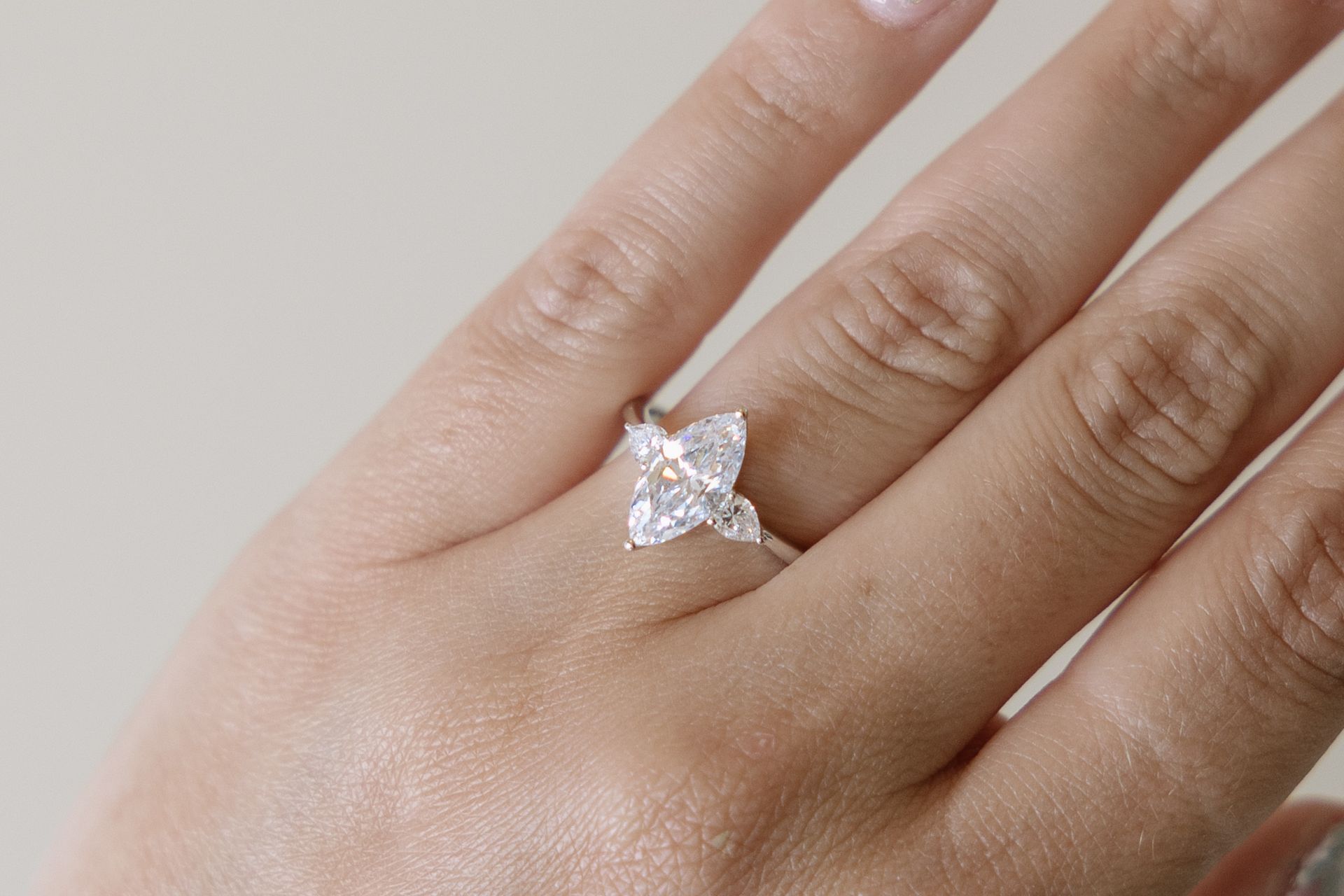 Hand with engagement ring; white gold band with pear and marquise cut diamonds.