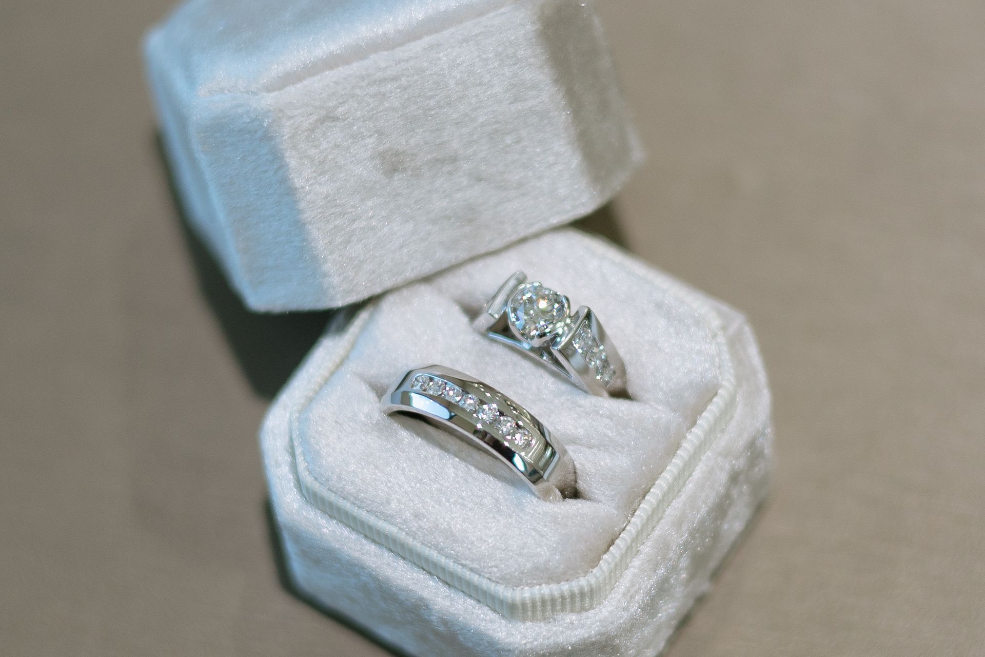 Two diamond rings in a velvet, hexagonal jewelry box, one with a large center stone.