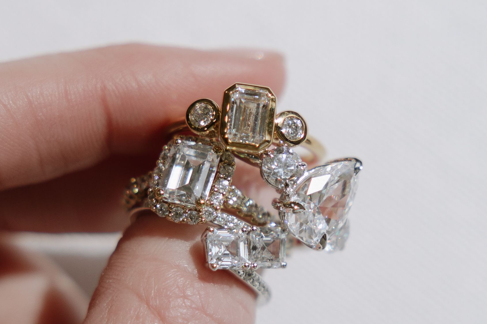 Hand holding a collection of sparkling diamond rings.