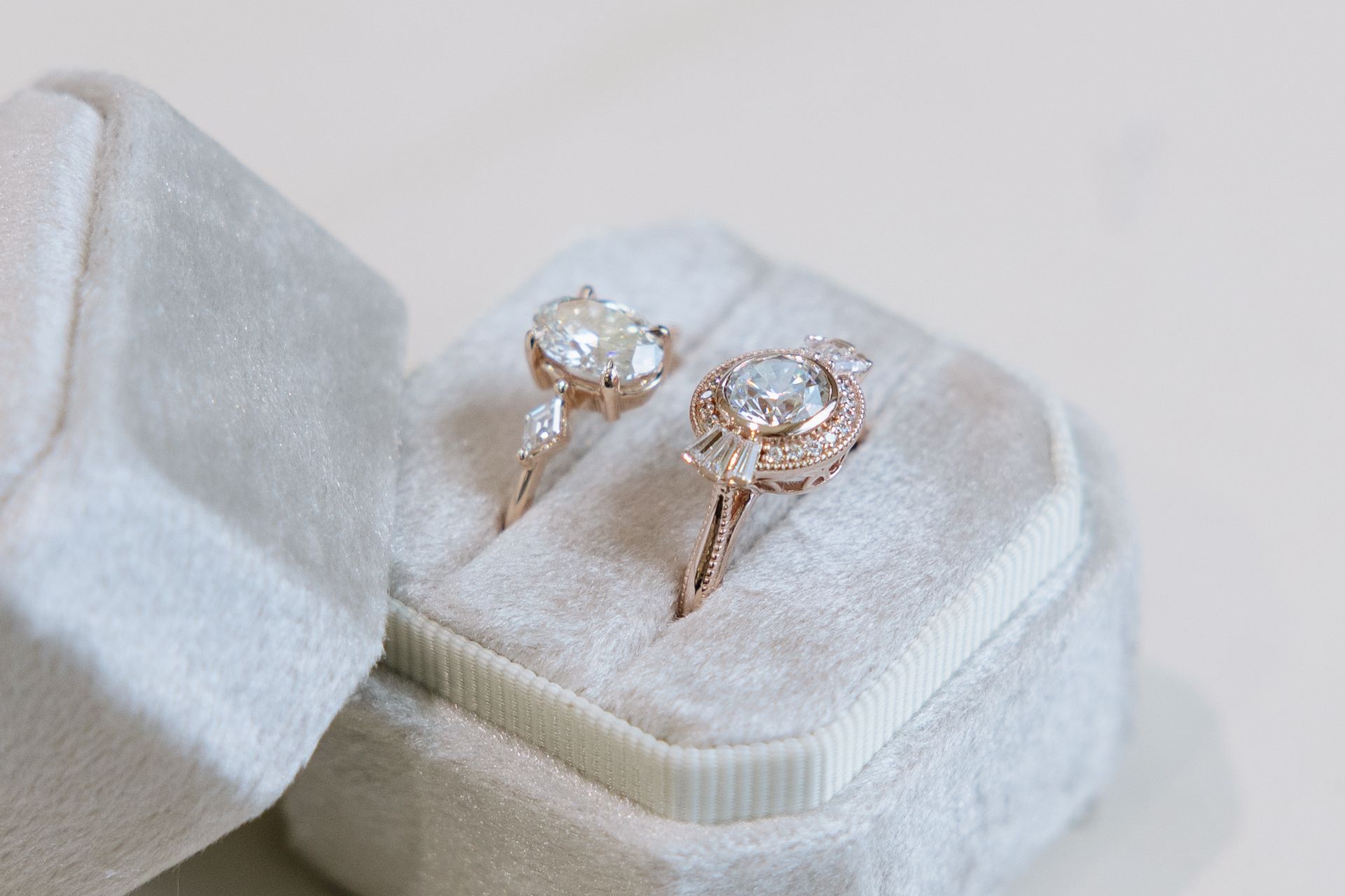 Two rose gold diamond rings in a gray velvet ring box.