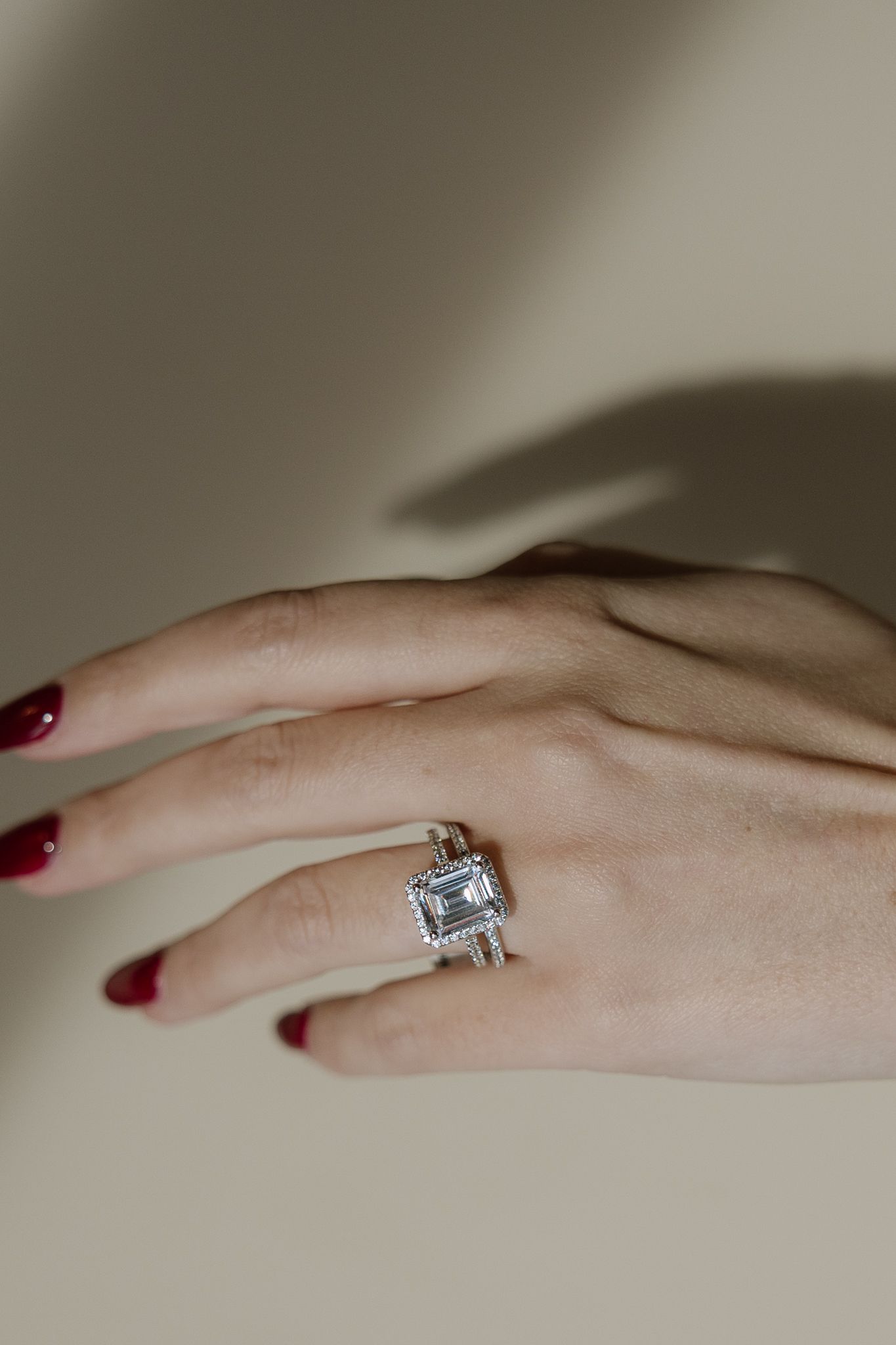 Hand wearing a large square gemstone ring with ornate silverwork; red nail polish.