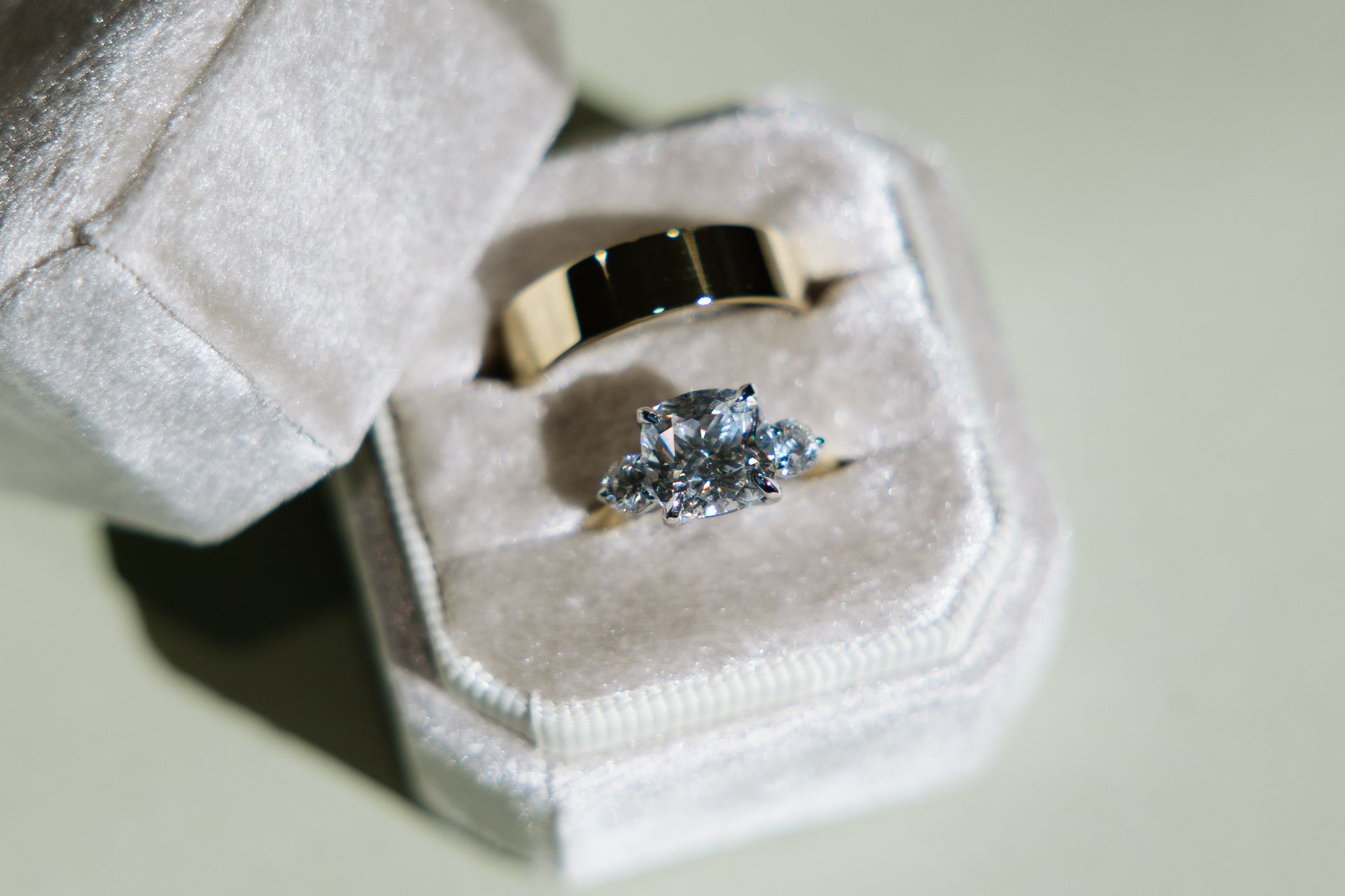 Wedding rings in a light beige velvet box; a diamond ring and a gold band.