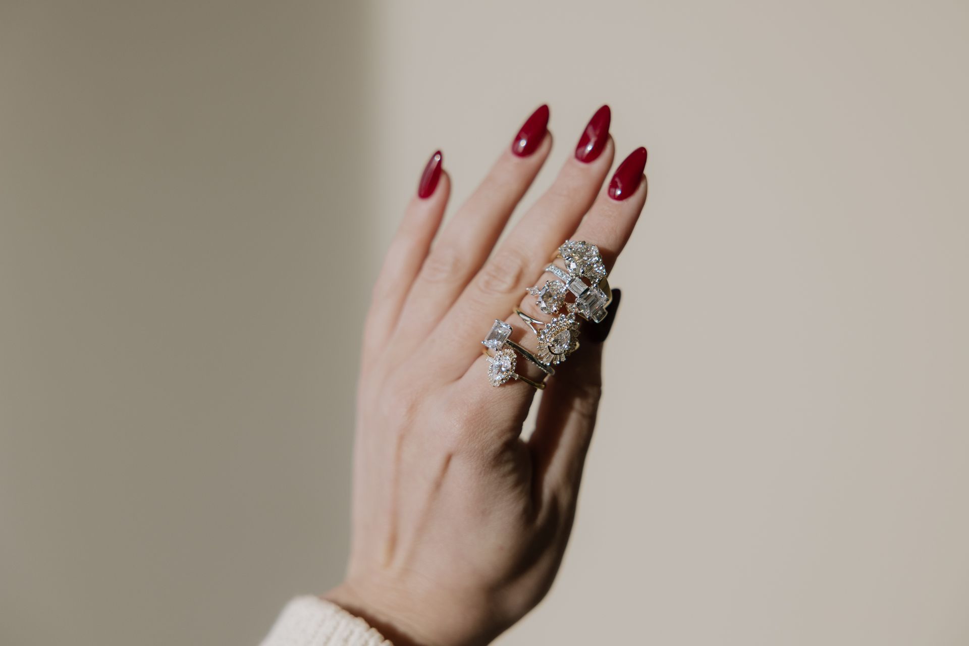 Hand with long, red nails, wearing a large, ornate silver ring.