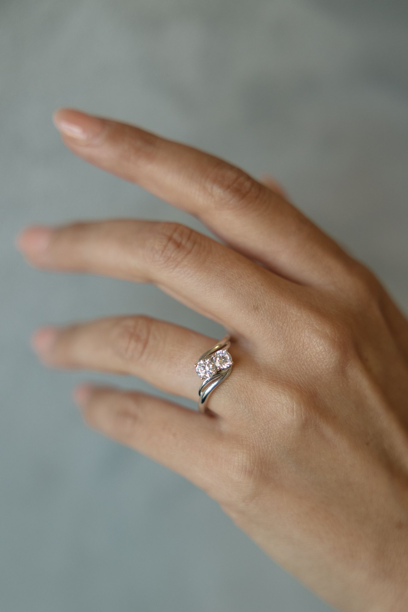 Hand wearing a silver engagement ring with a pink square-cut stone.