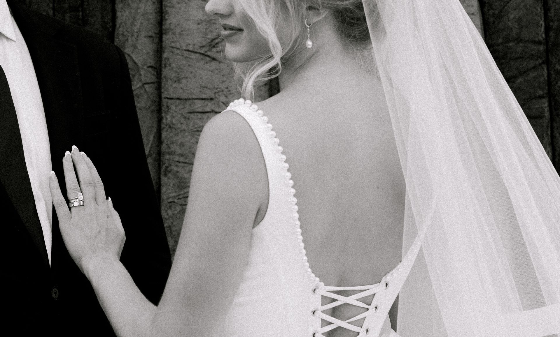 Hand wearing a gold engagement ring with a central pear-shaped diamond and surrounding smaller stones.