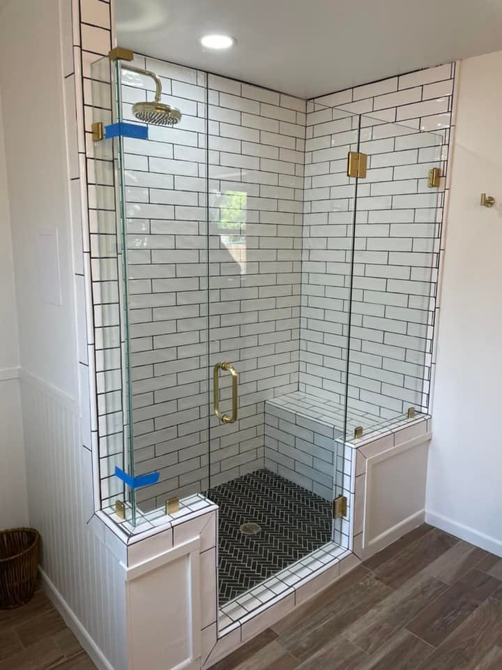 A bathroom with white brick walls and a walk in shower with a glass door.