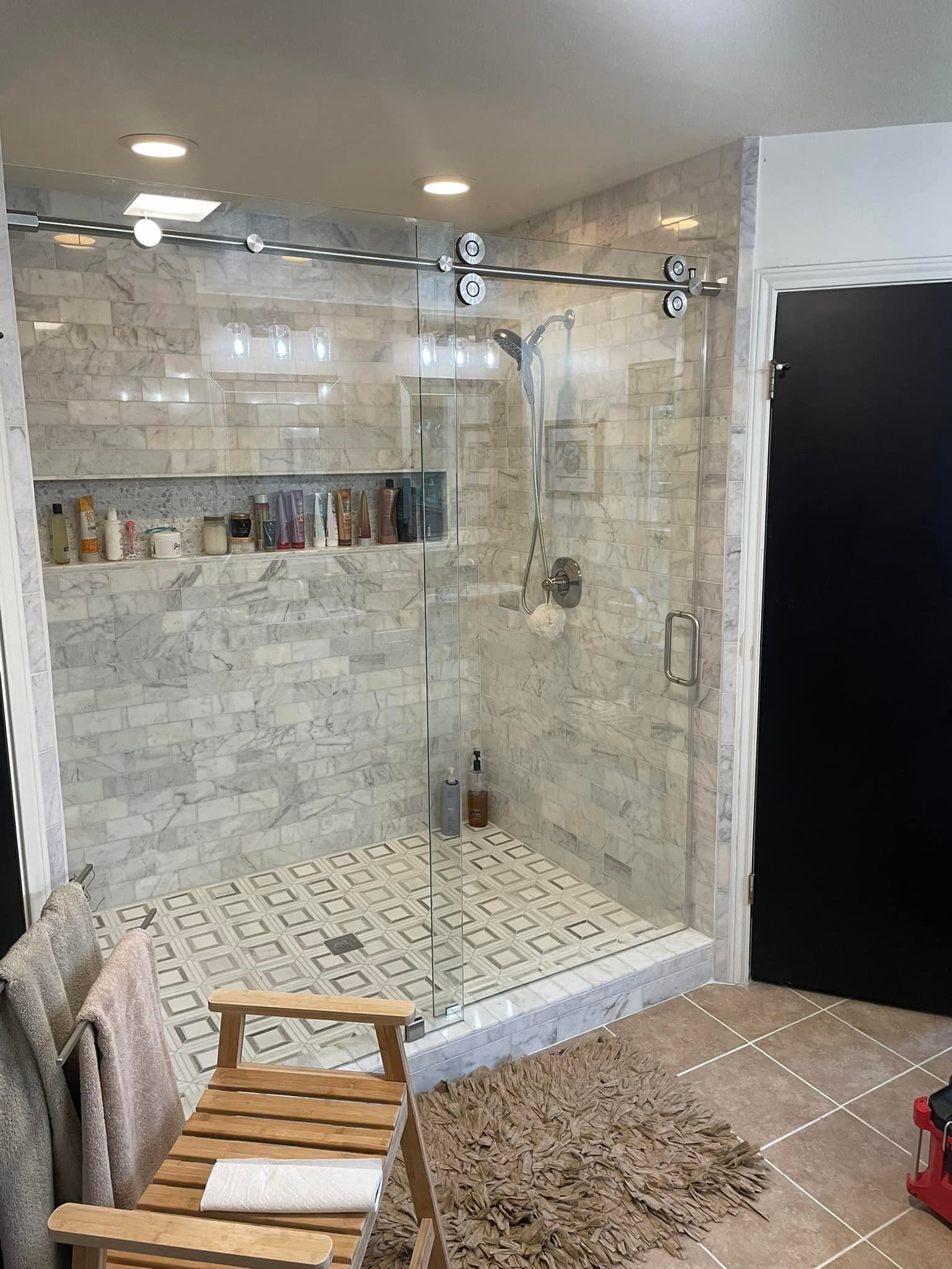 A bathroom with a walk in shower and a wooden chair.