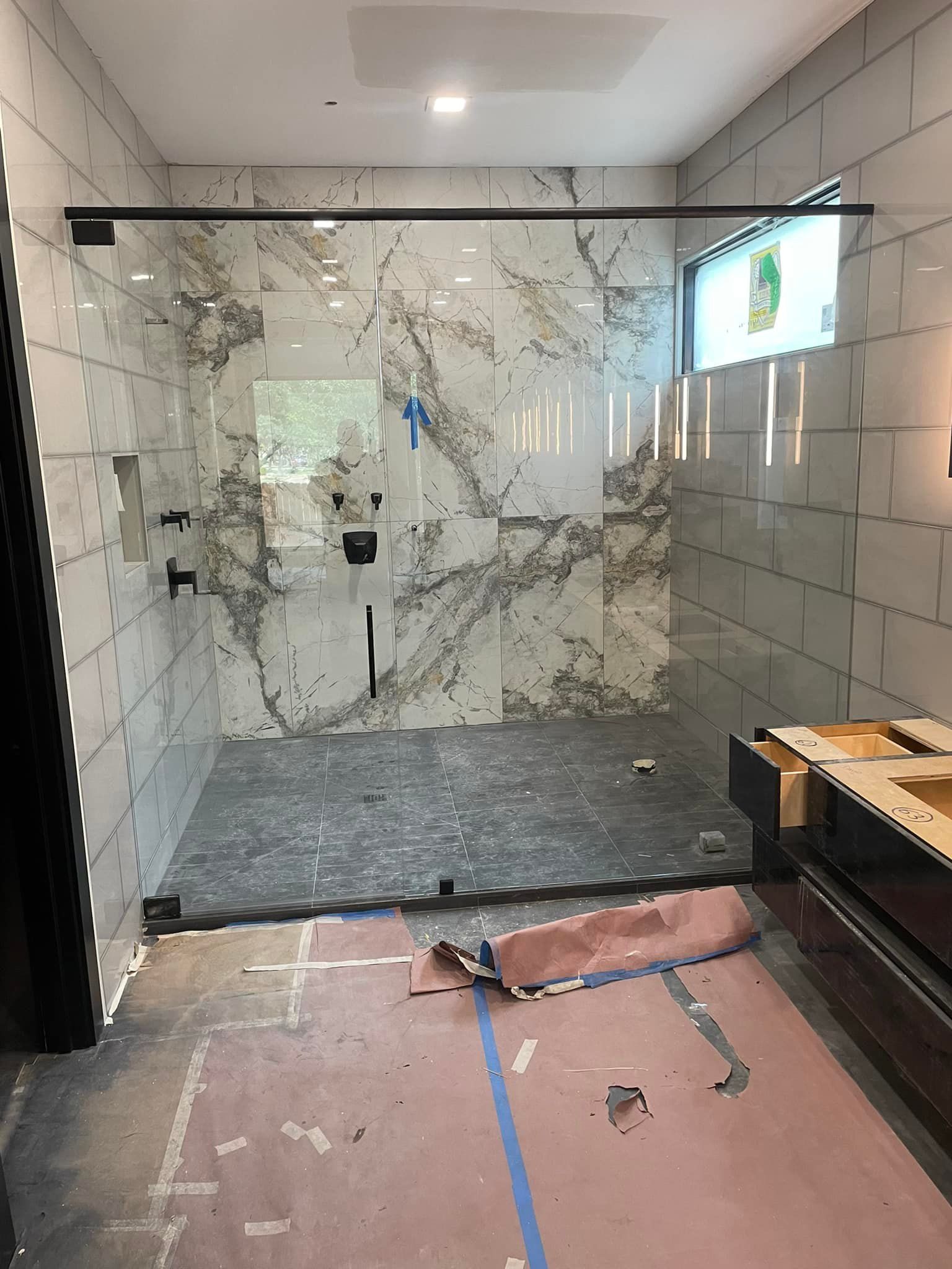 A bathroom with marble tiles and a walk in shower with a glass door.