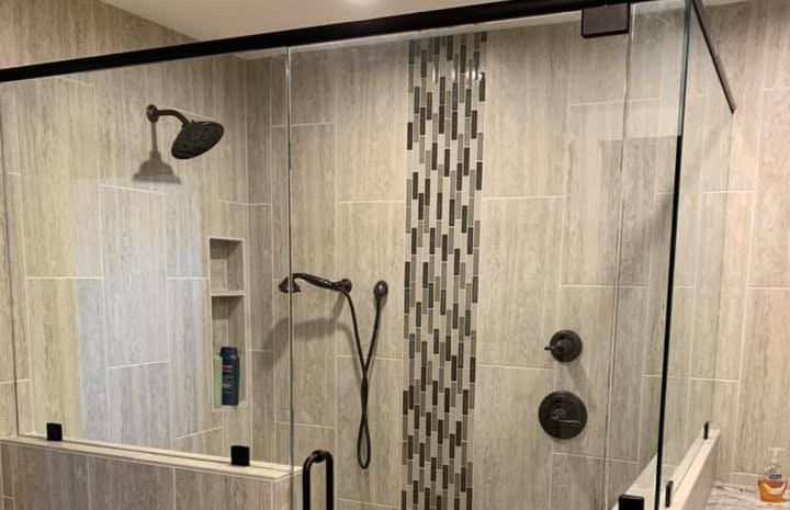 A bathroom with a walk in shower with a glass door.