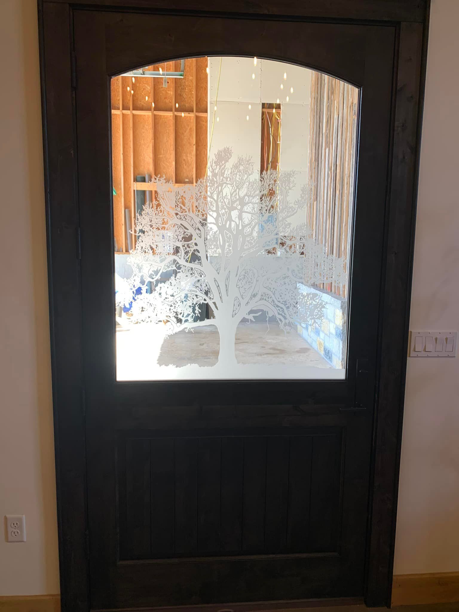 A wooden door with a glass window and a tree design on it.