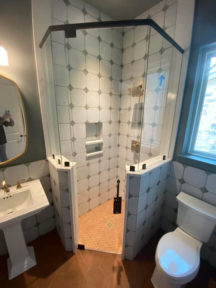 A bathroom with a walk in shower , toilet , sink and mirror.