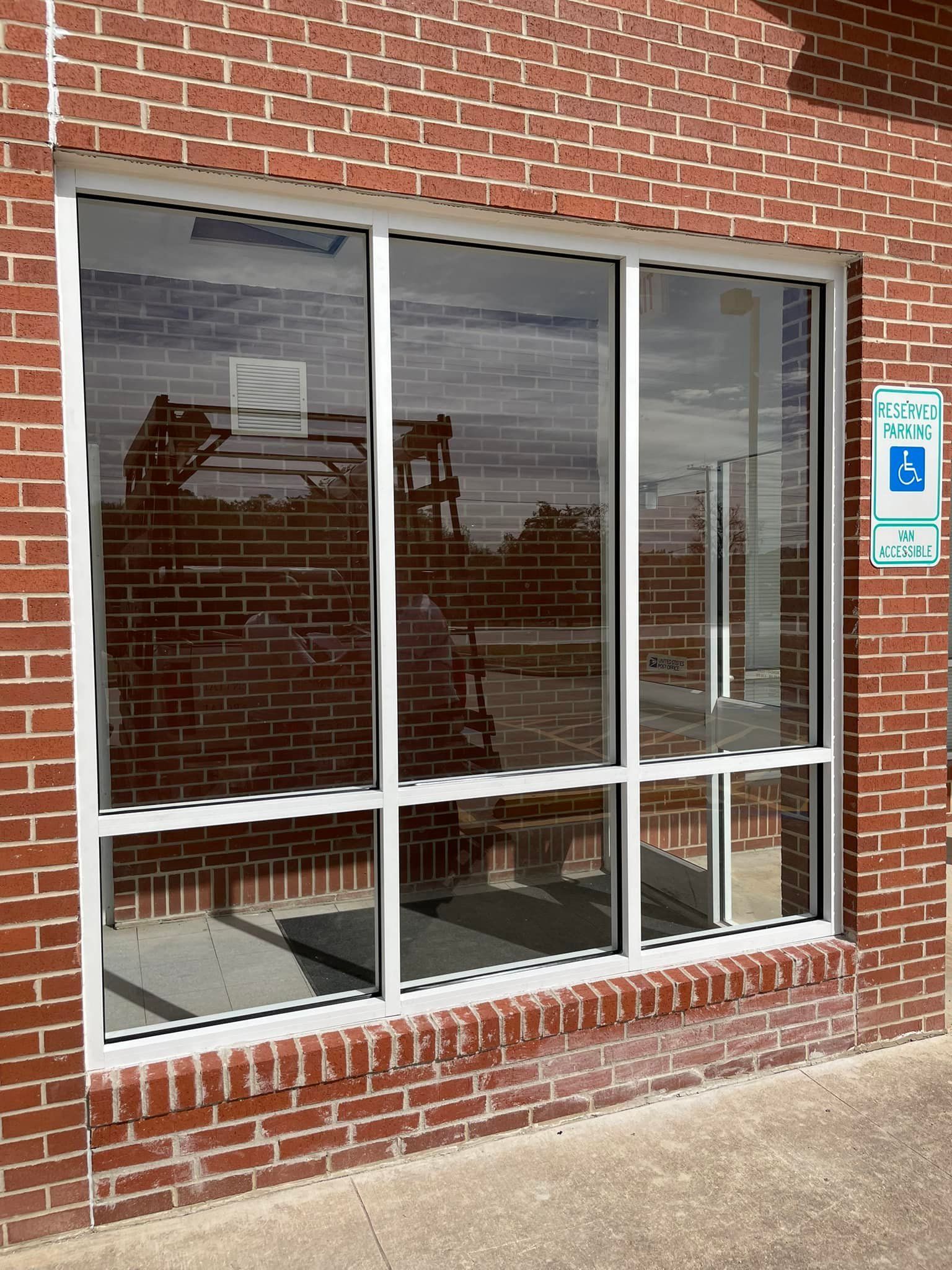 A brick building with a large window and a handicap sign.