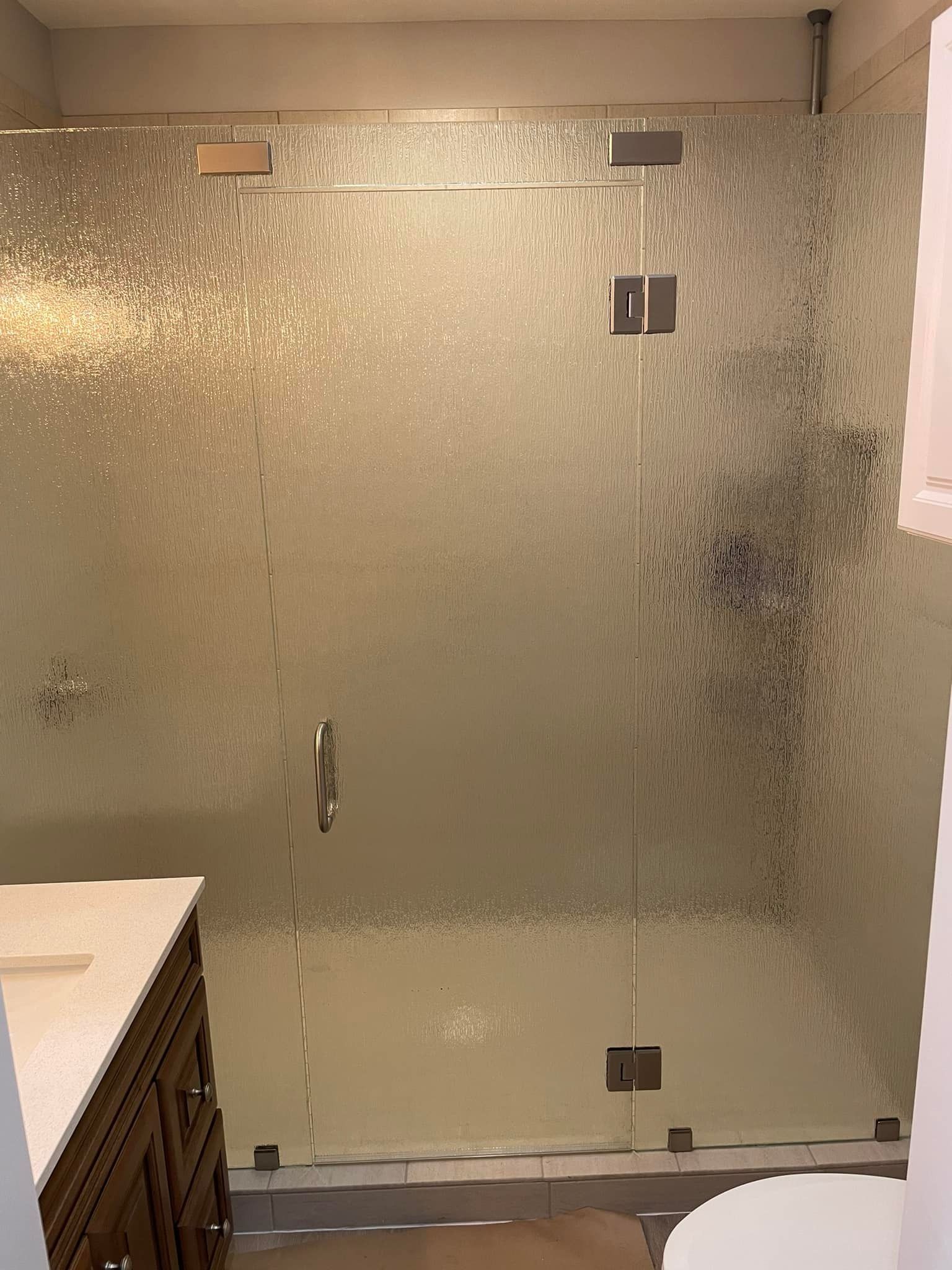 A bathroom with a glass shower door and a toilet.