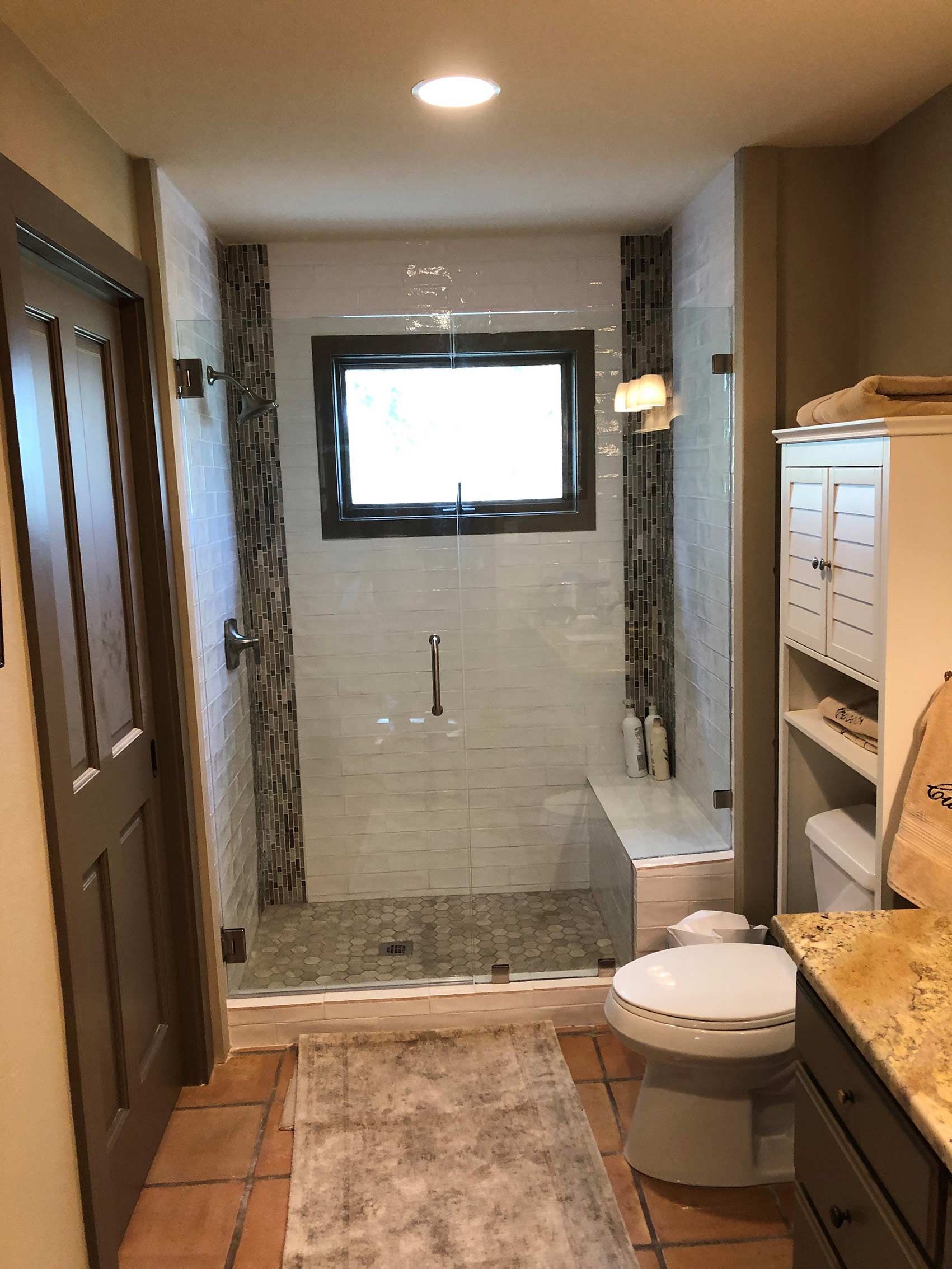 A bathroom with a toilet , sink , shower and window.