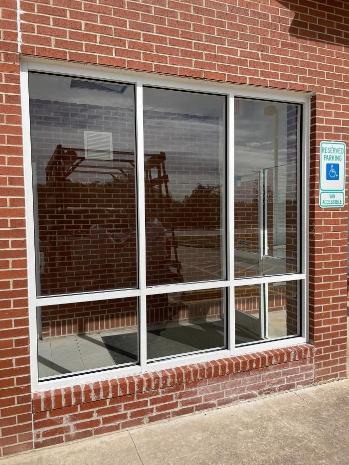 A brick building with a large window and a handicapped parking sign.