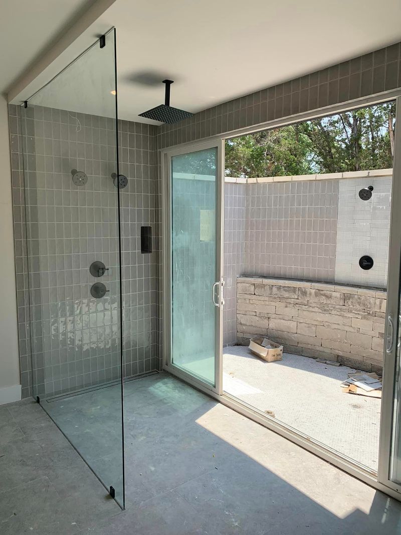 A bathroom with a walk in shower and a sliding glass door.