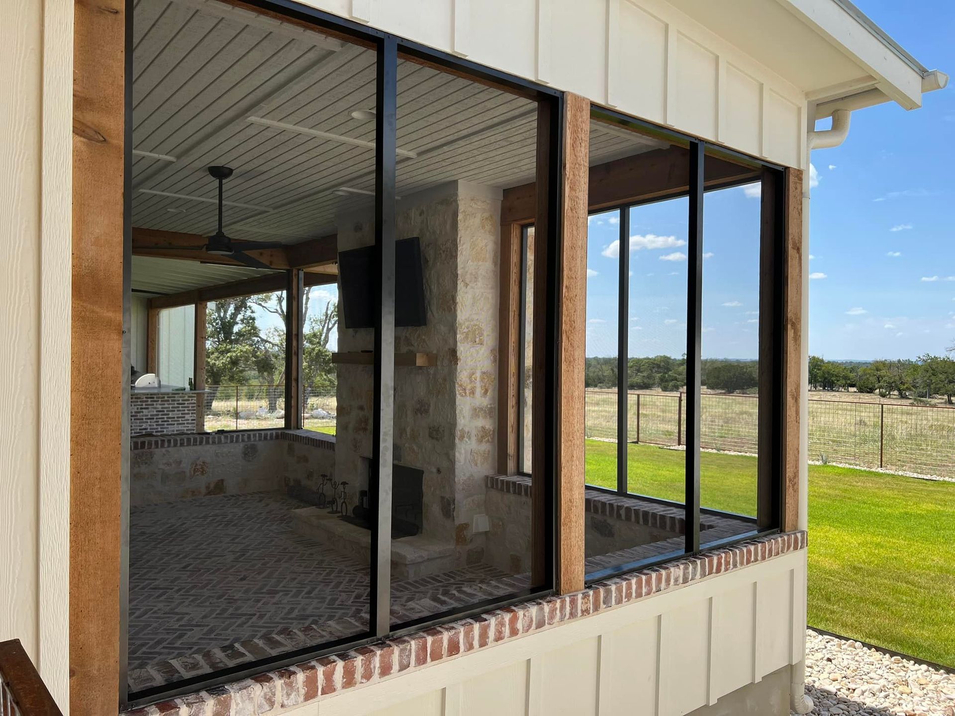 A screened in porch with a lot of windows and a fireplace.